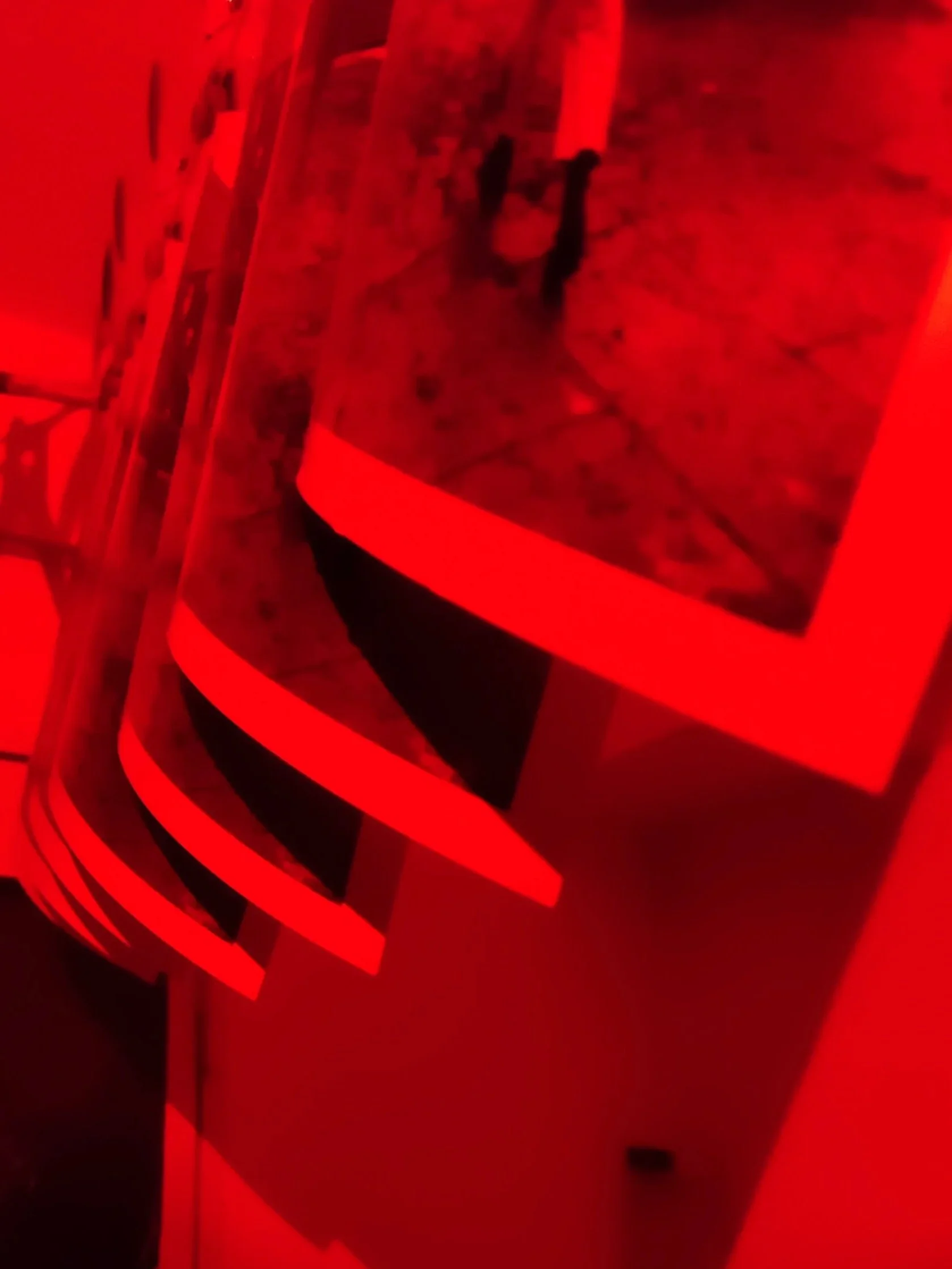 Black and white photographic prints hanging in a dark room in red light.