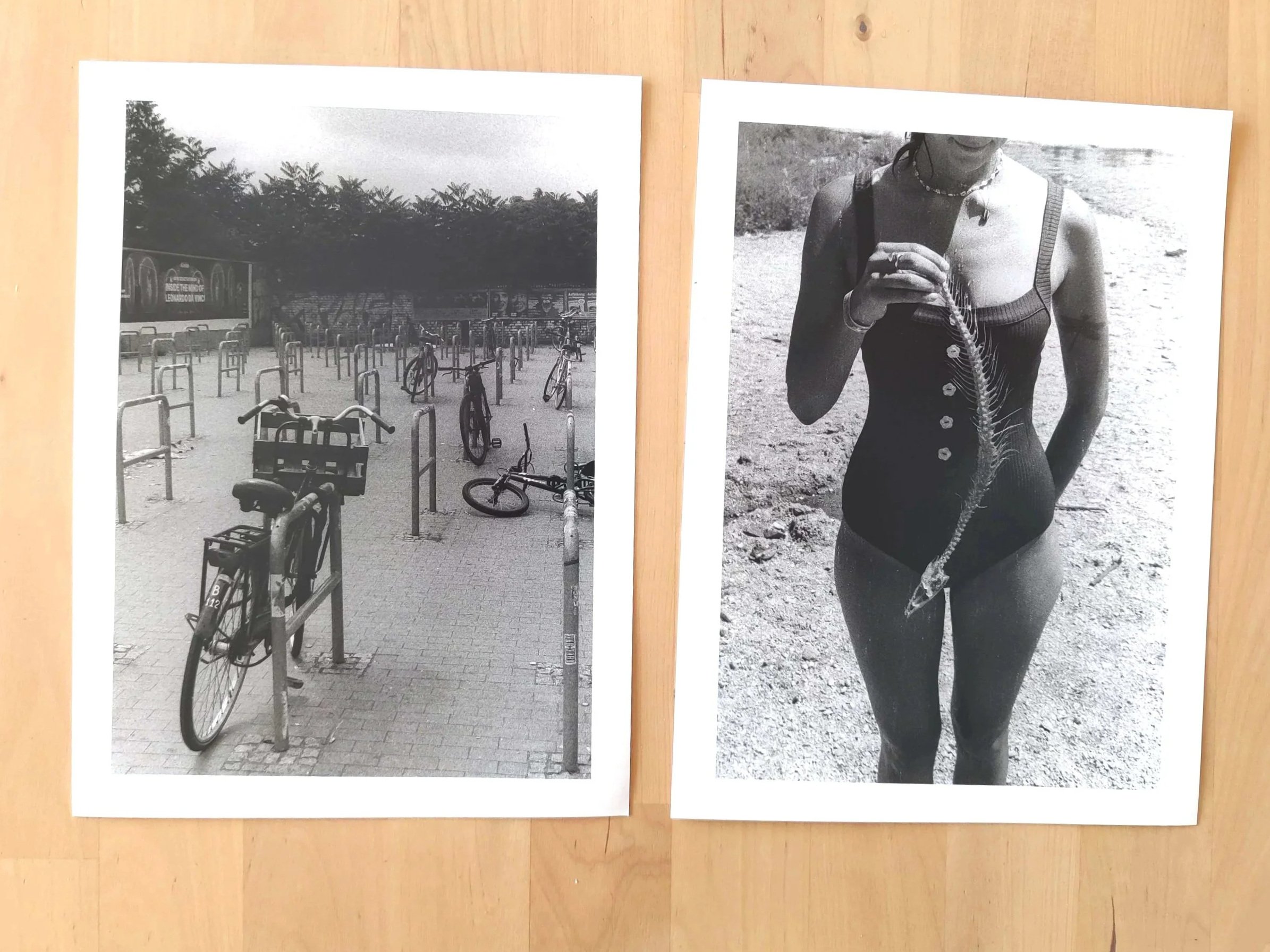 Two black and white photographic prints on a wooden table