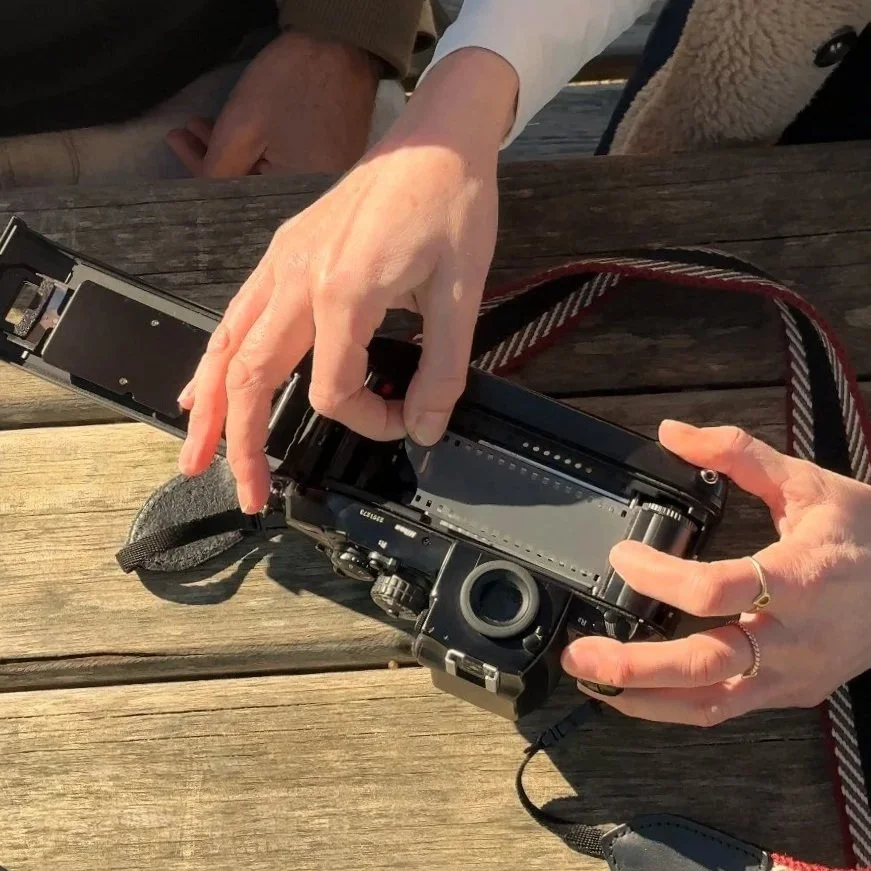 A person loading a camera with film on a wooden table