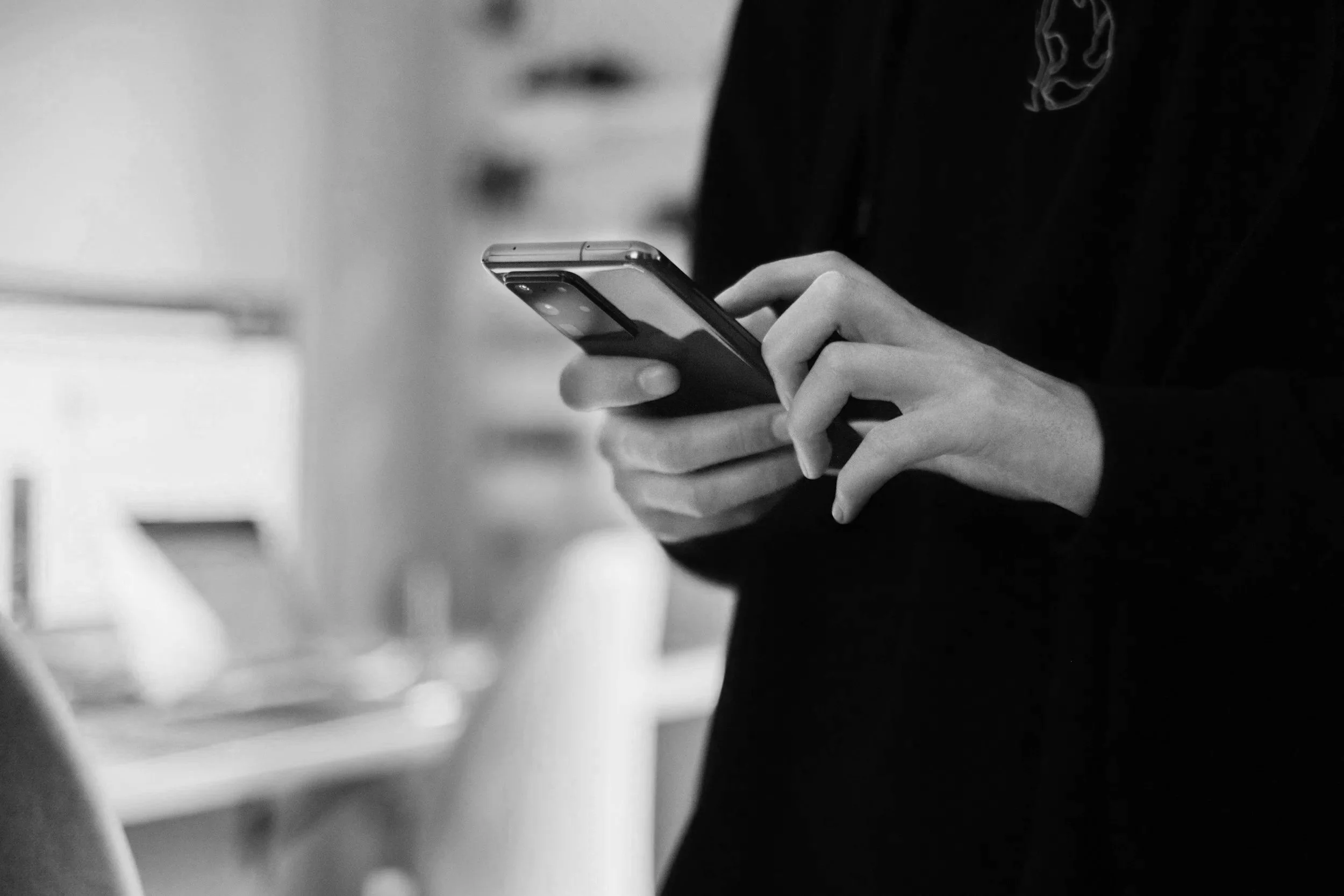 A person scrolling on a smartphone in black and white.
