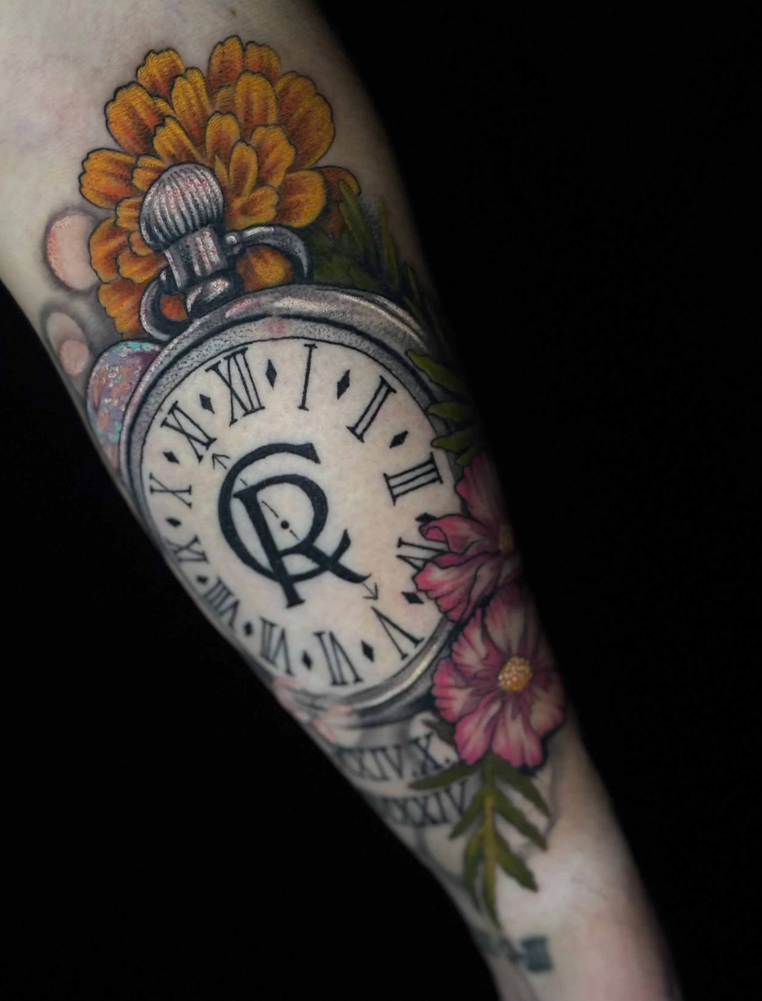 Tattoo of a pocket watch with floral designs, including pink and orange flowers.