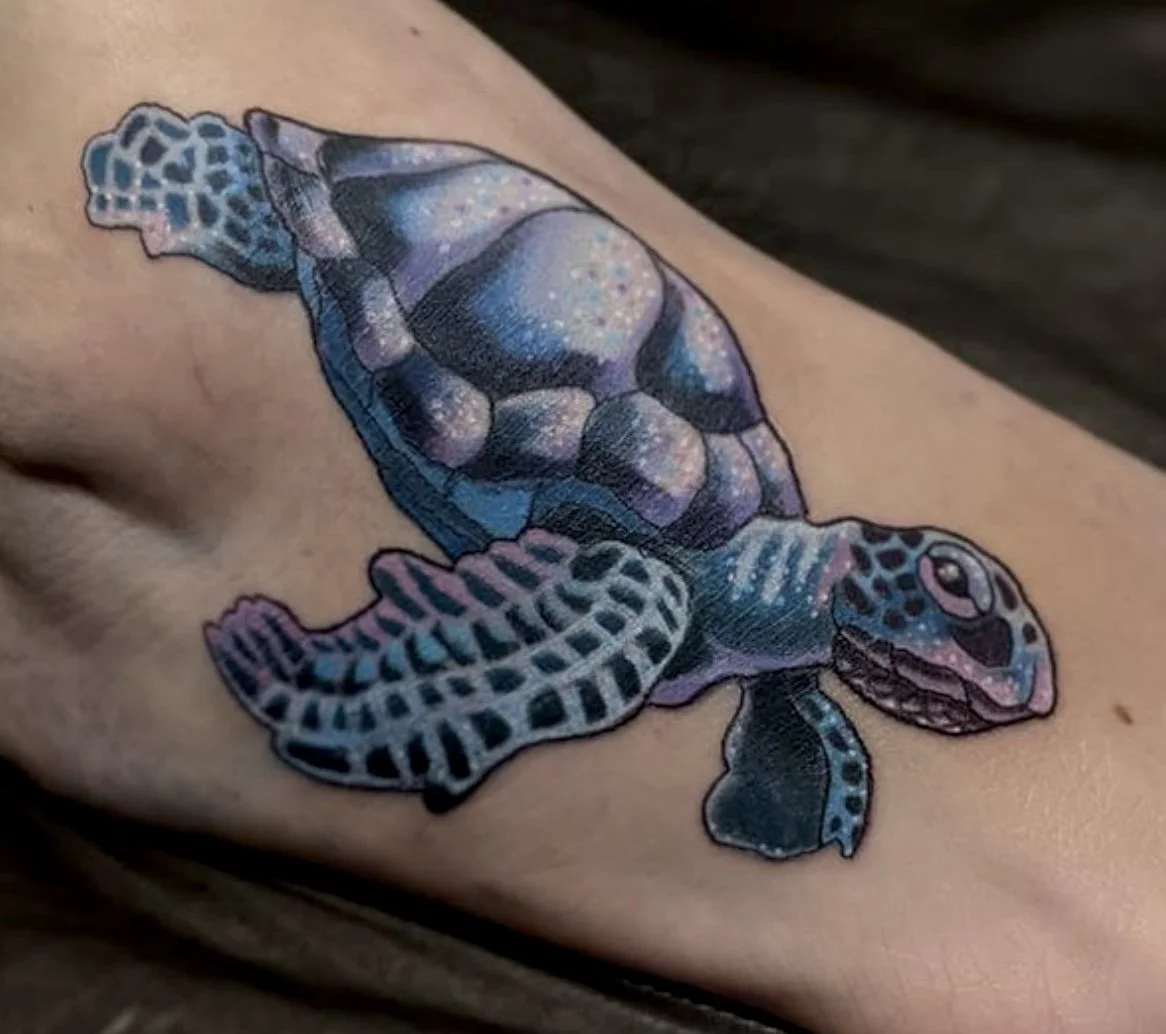 Colorful tattoo of a baby sea turtle on skin, featuring a galaxy-like pattern with stars and cosmic colors.