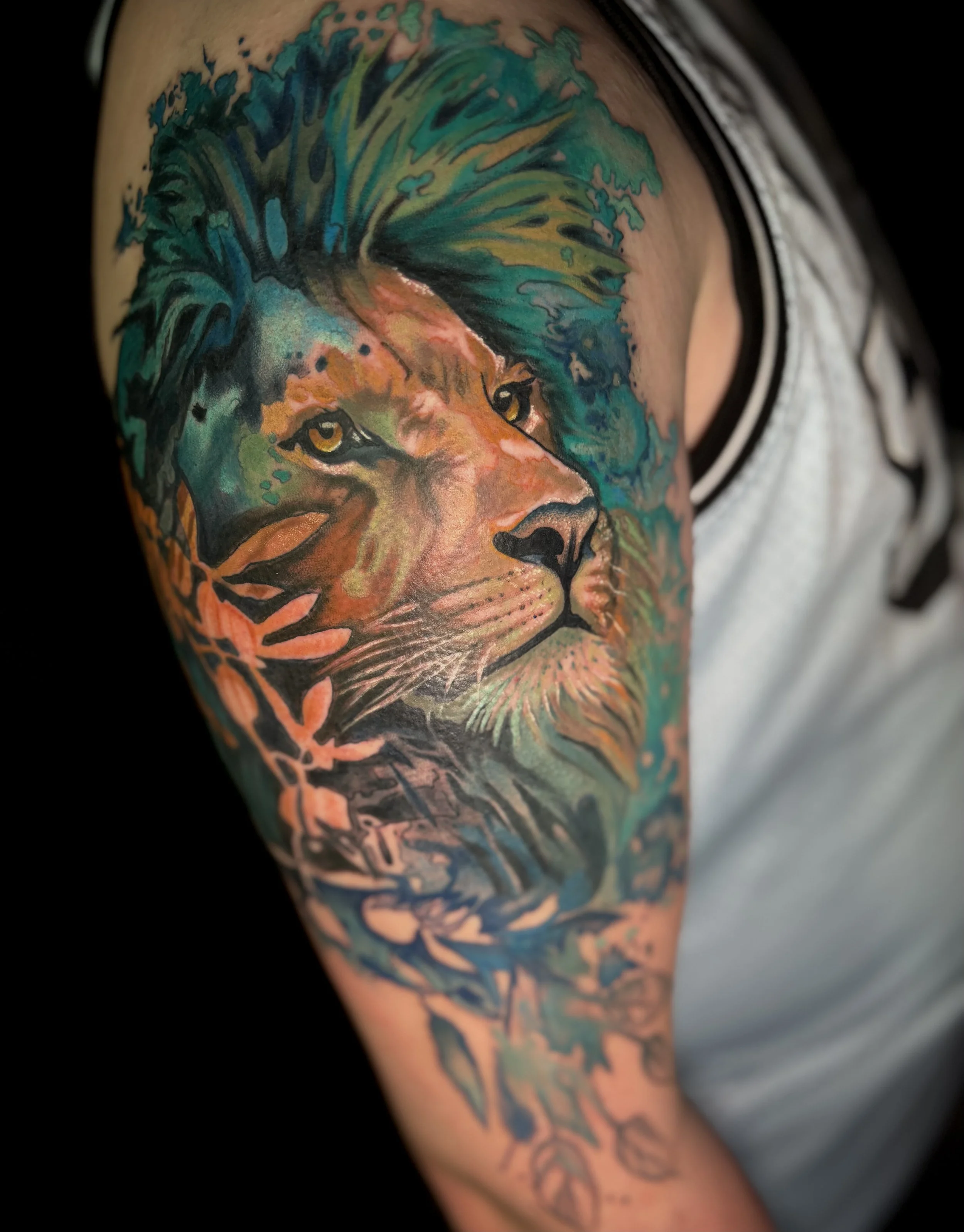 Colorful tattoo of a lion's face on a person's upper arm.