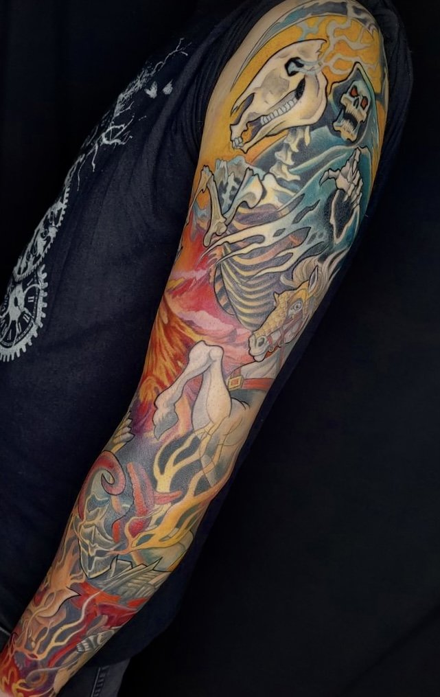 Colorful tattoo sleeve featuring a dragon, a skeleton with a horse's head, a wolf, and fire elements on an arm.