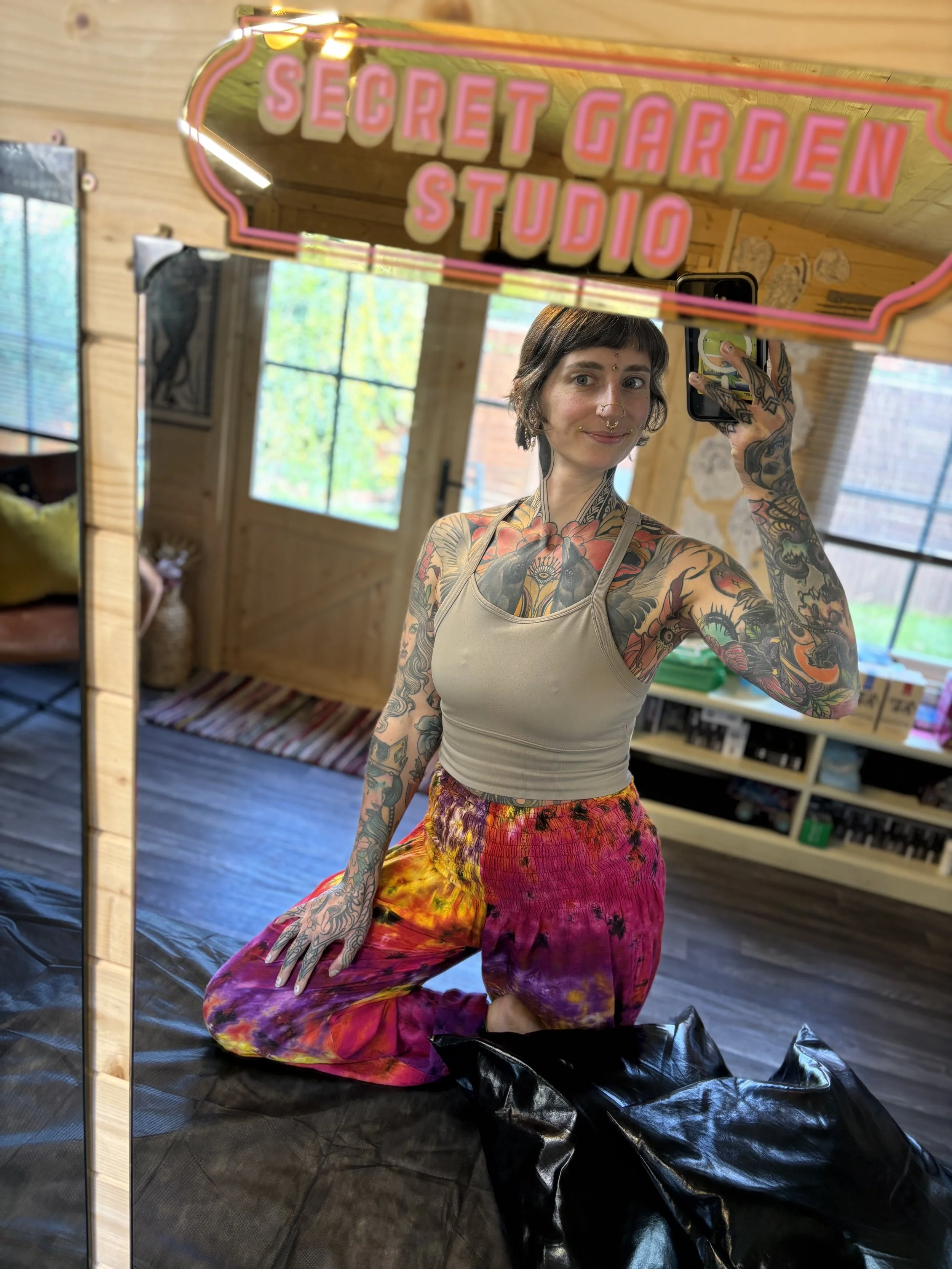 Photo of tattoo artist tattooed woman with tie dye clothes