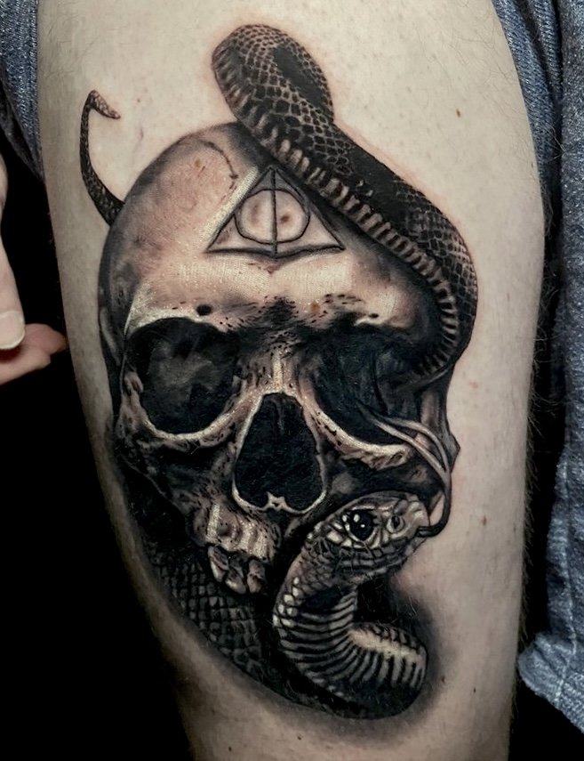 Tattoo of a human skull with a snake coiled around it, and a pyramid with an eye inside it above the skull.