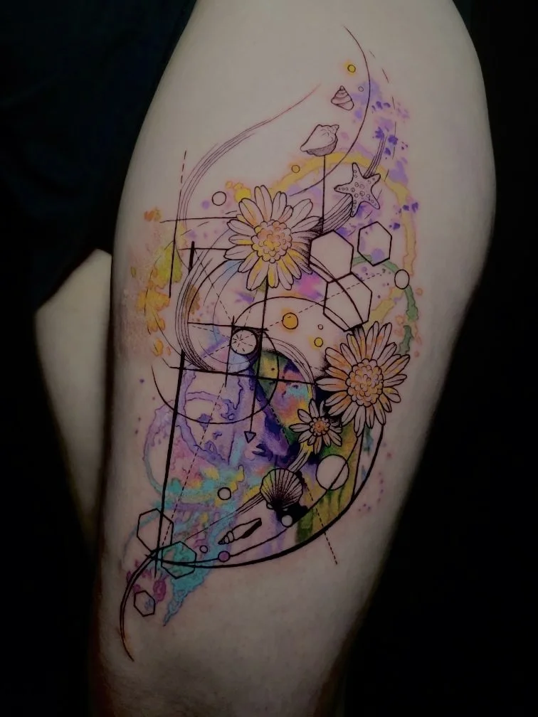 Colorful tattoo featuring geometric shapes, flowers, seashells, starfish, and abstract watercolor-style splashes on skin.