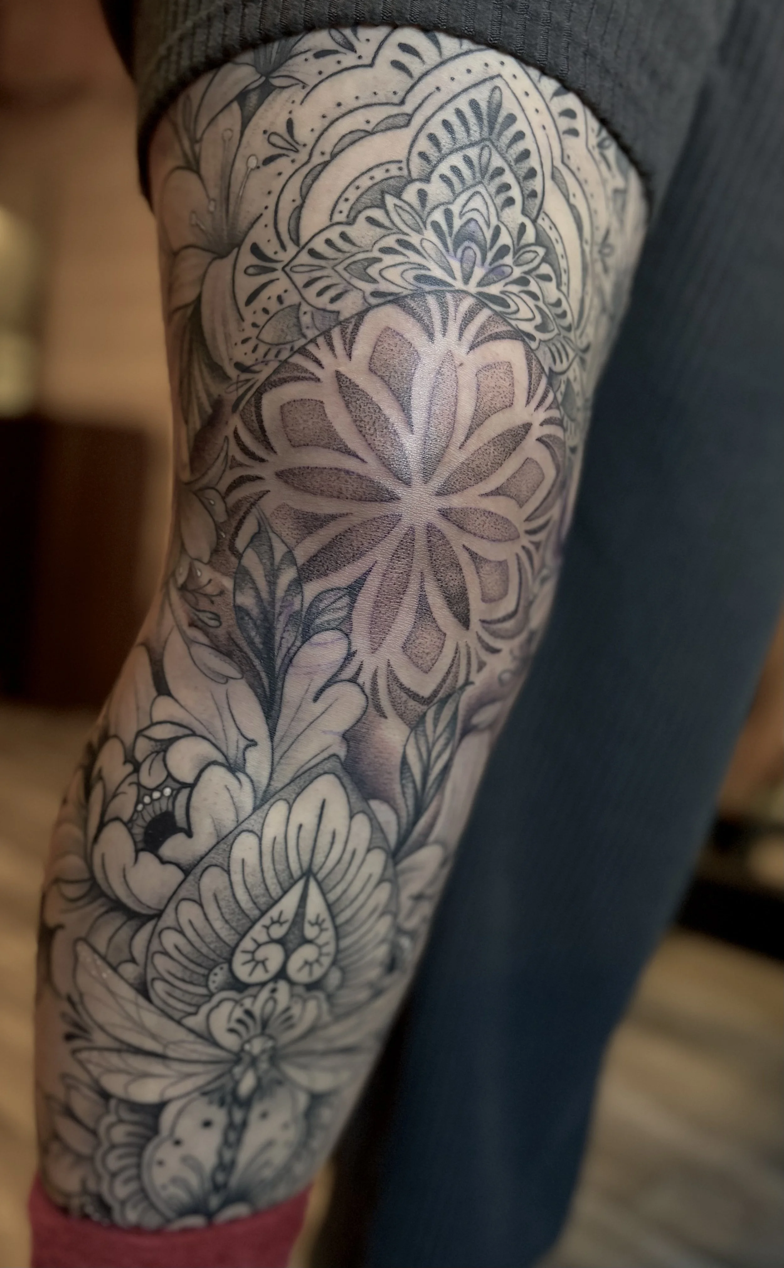 Close-up of a person's arm with an intricate black and gray floral tattoo sleeve.