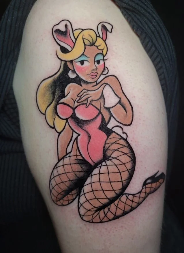 Tattoo of a cartoonish woman with bunny ears, fishnet stockings, and a revealing outfit, posed in a suggestive manner.