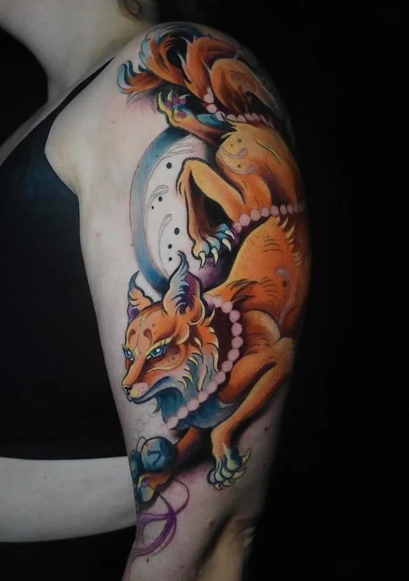 Colorful tattoo of a fox and a snake on a person's upper arm and shoulder.