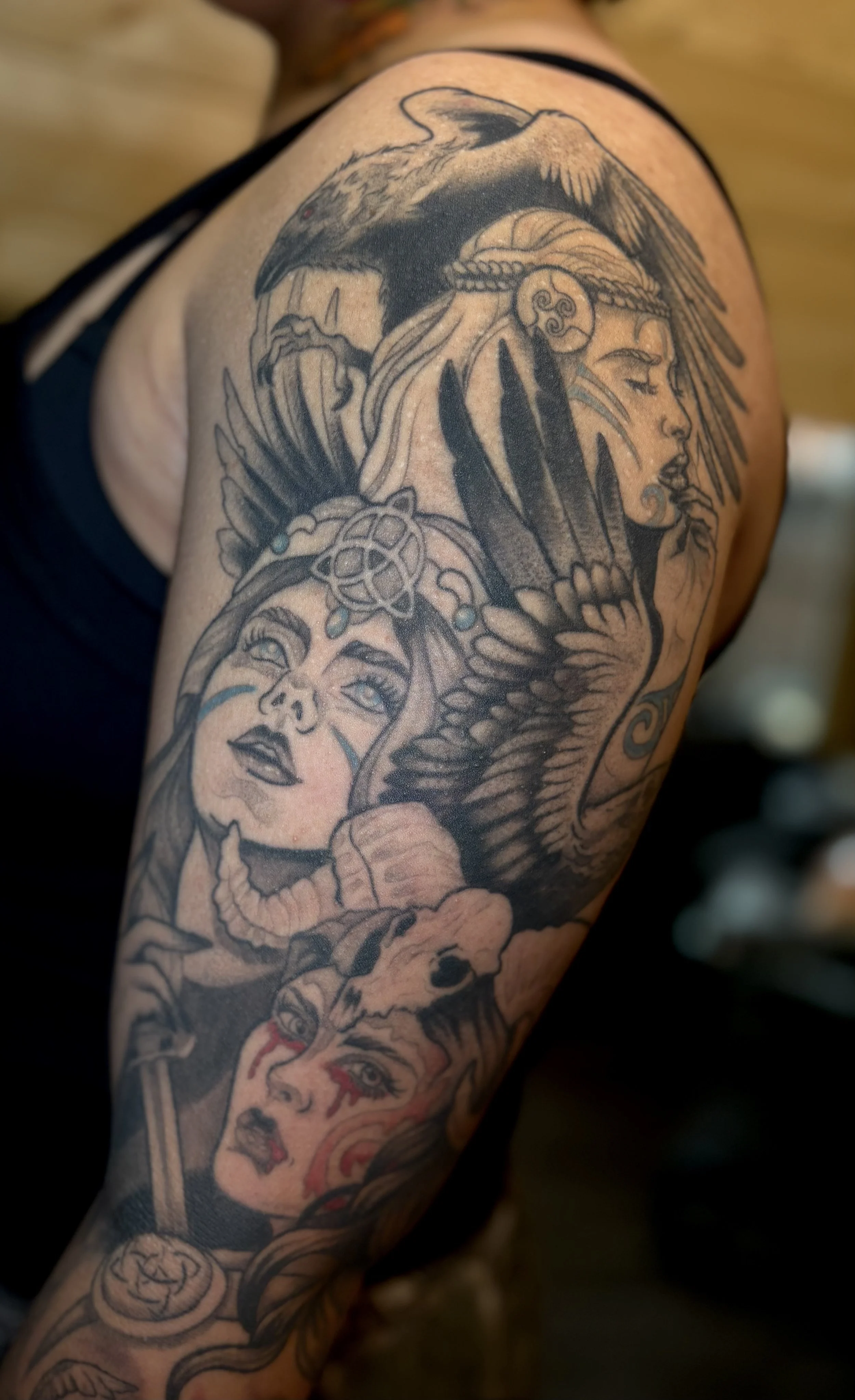 Tattoo sleeve featuring a Raven, a Native American woman with a feather headdress, a woman with face paint, and a wolf skull.