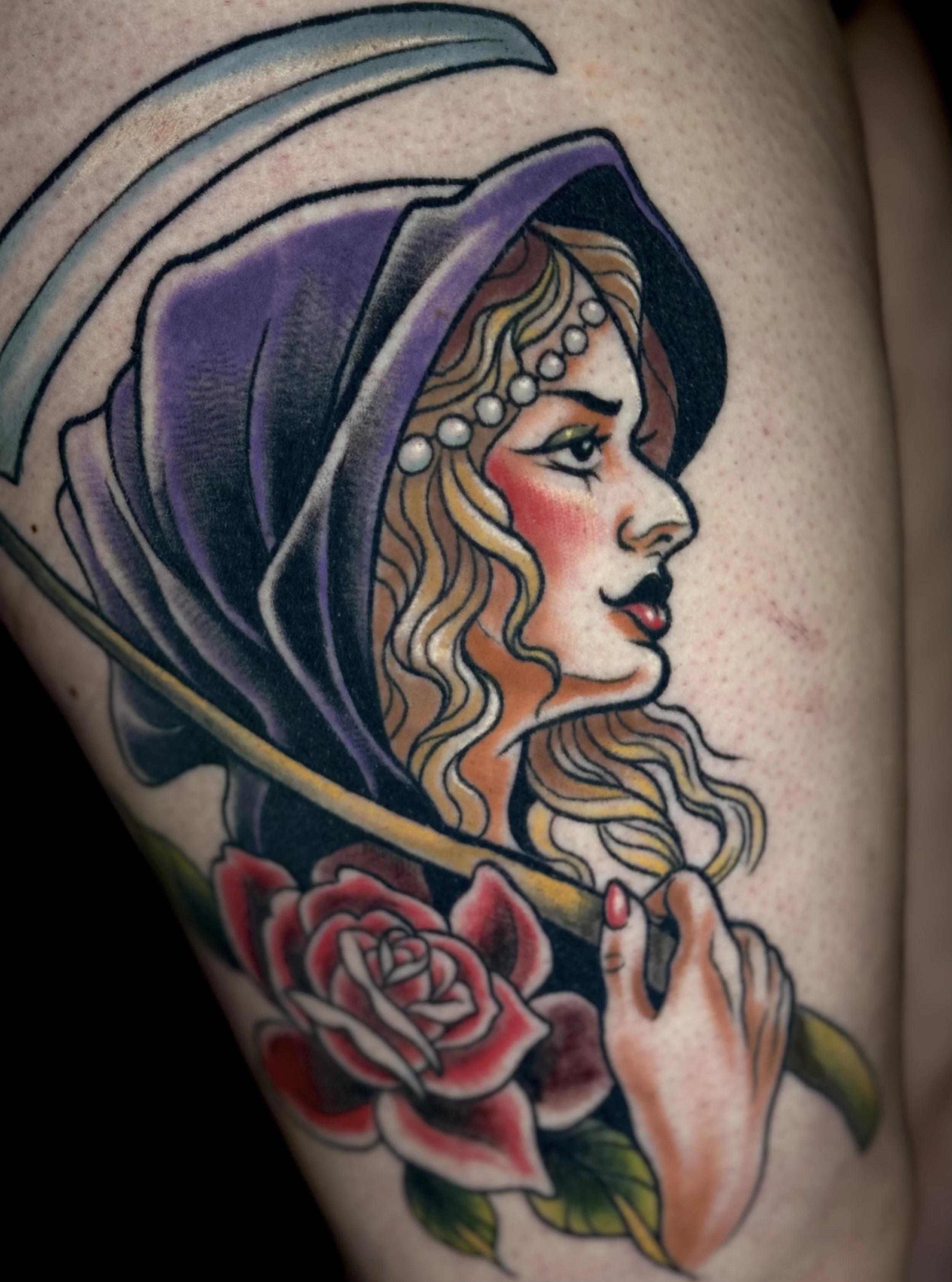 Tattoo of a woman in profile with long blonde hair, wearing a purple hooded cloak and a pearl headband, holding a rose in her hand.