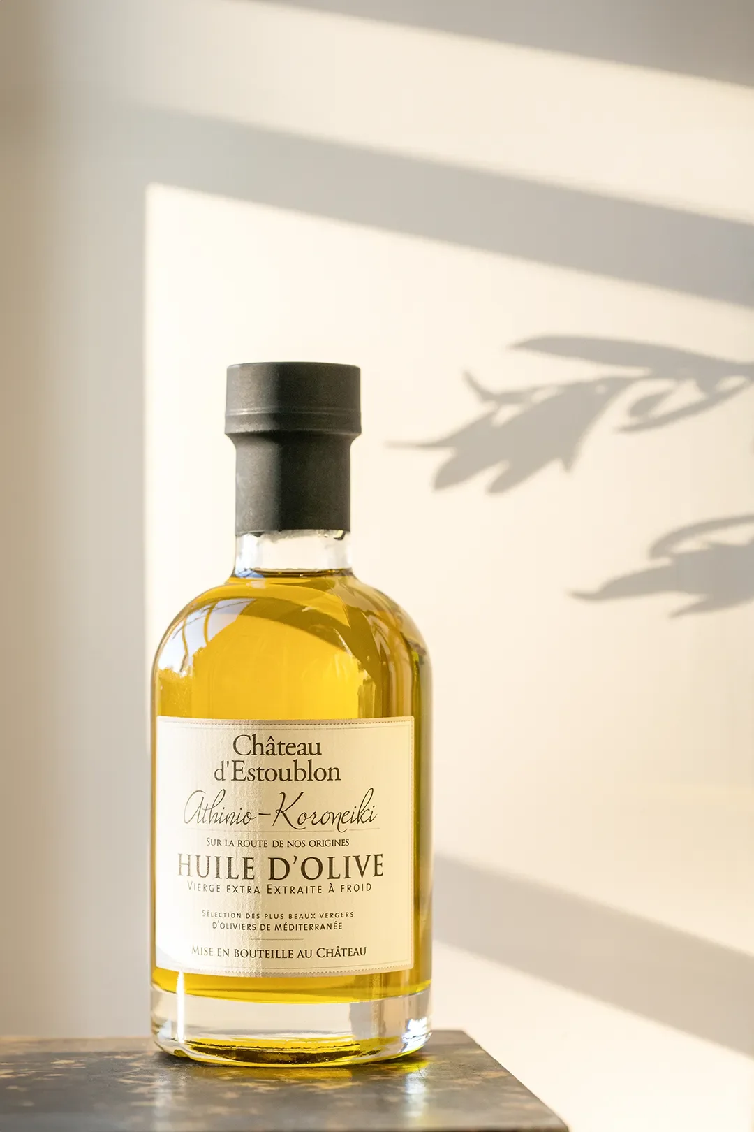 Bouteille d'huile d'olive Château d'Estoublon, avec un fond de lumière et d'ombre.