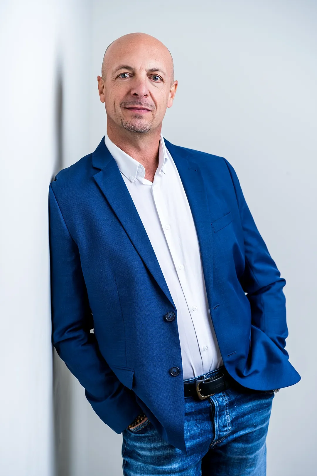 Homme d'affaires en costume bleu clair avec chemise blanche, posant dans un bureau.