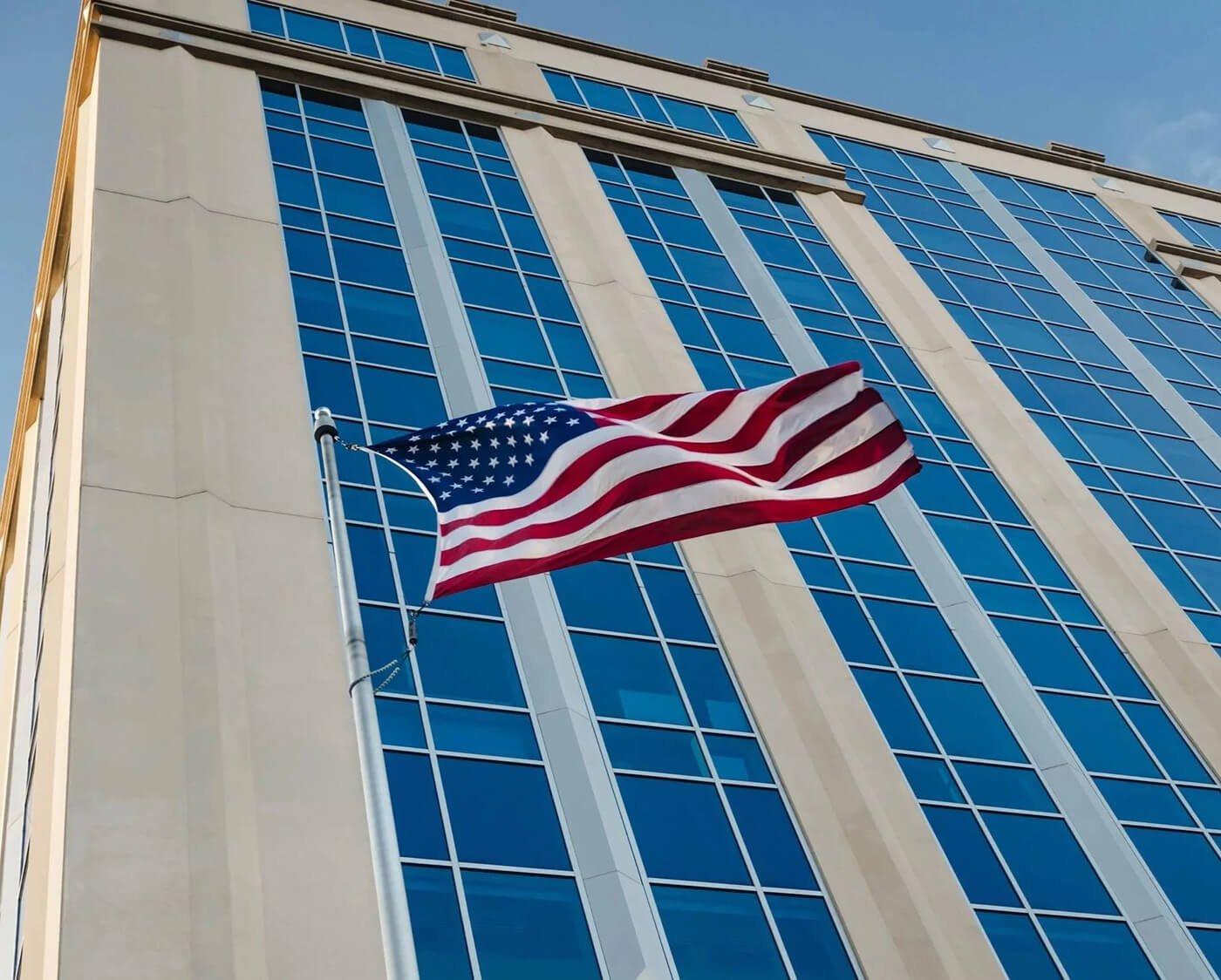 American flag flying in front of a downtown office building, representing community investment and local impact.