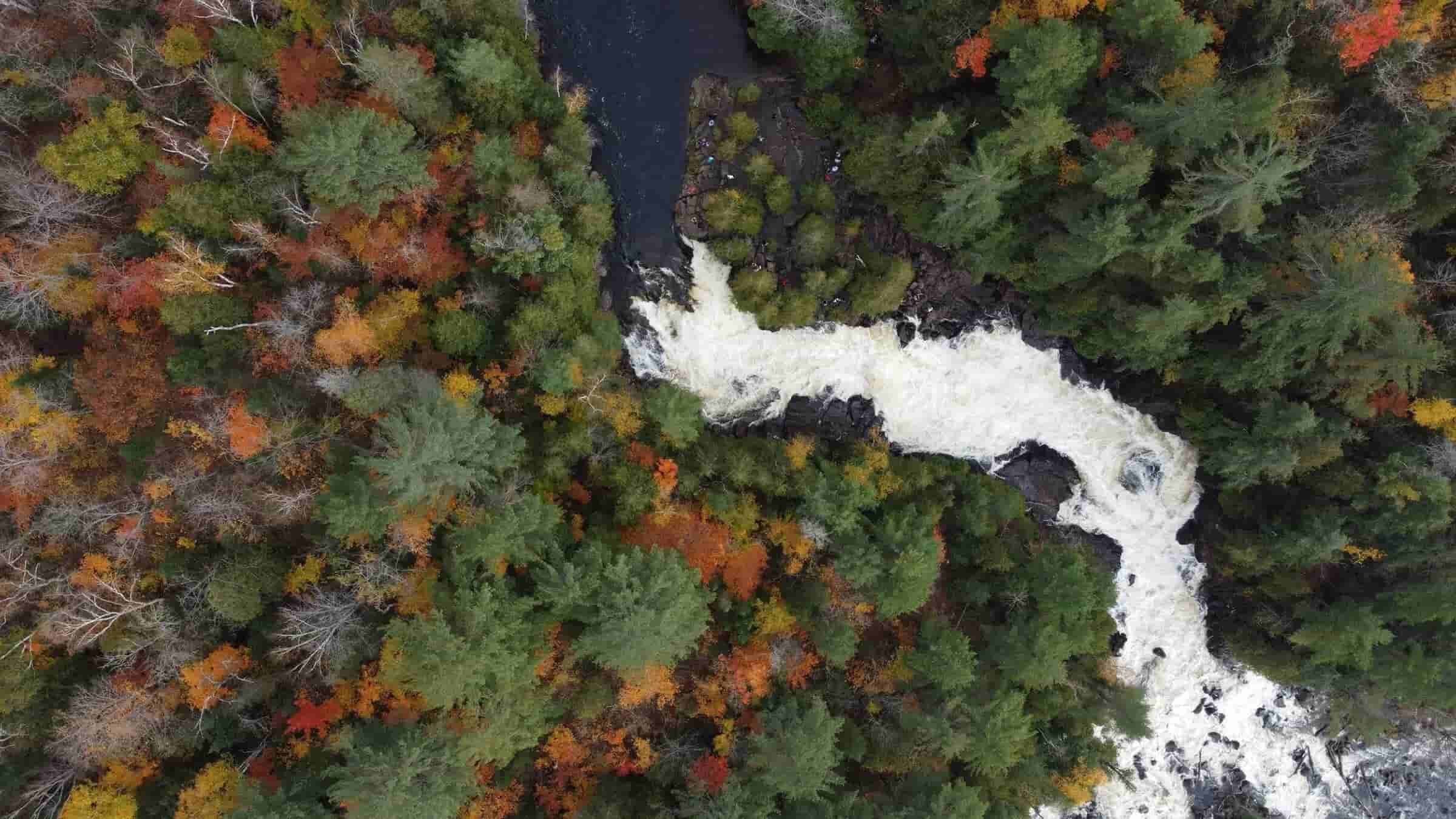 Aerial view of a river flowing through forest landscape in Wisconsin during fall.