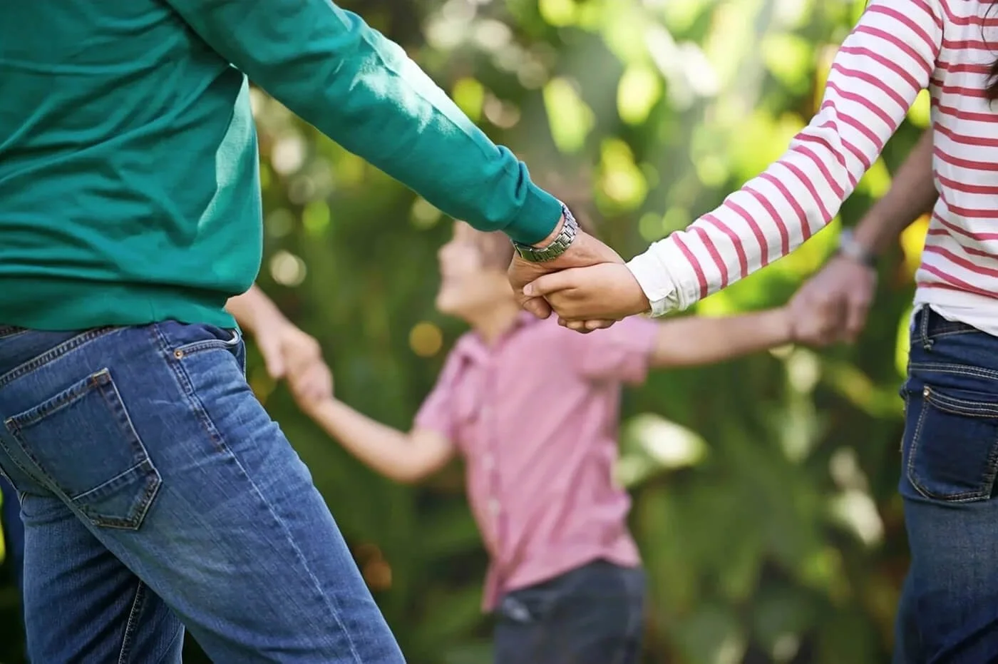 People holding hands outdoors, representing community connection and local impact.