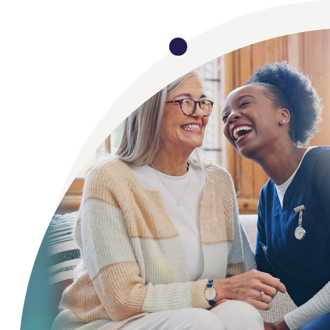 An elderly woman and a young nurse sharing a joyful moment, smiling and laughing together indoors.