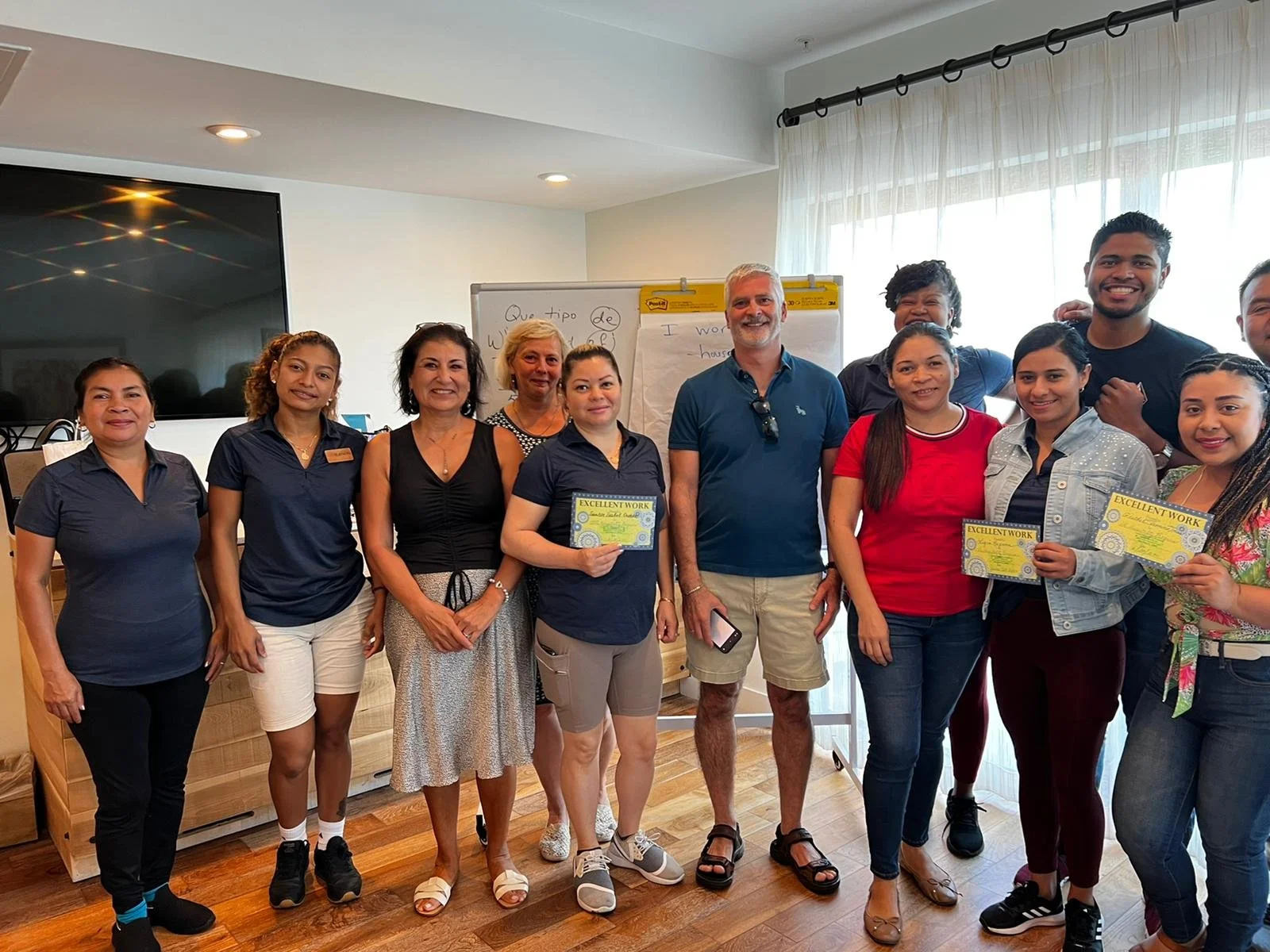 Group of people standing indoors, some holding certificates, smiling for a photo.