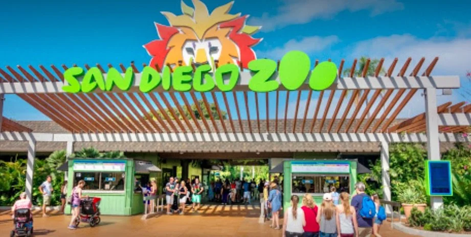 Entrance of the San Diego Zoo with visitors entering and a lion logo sign overhead.
