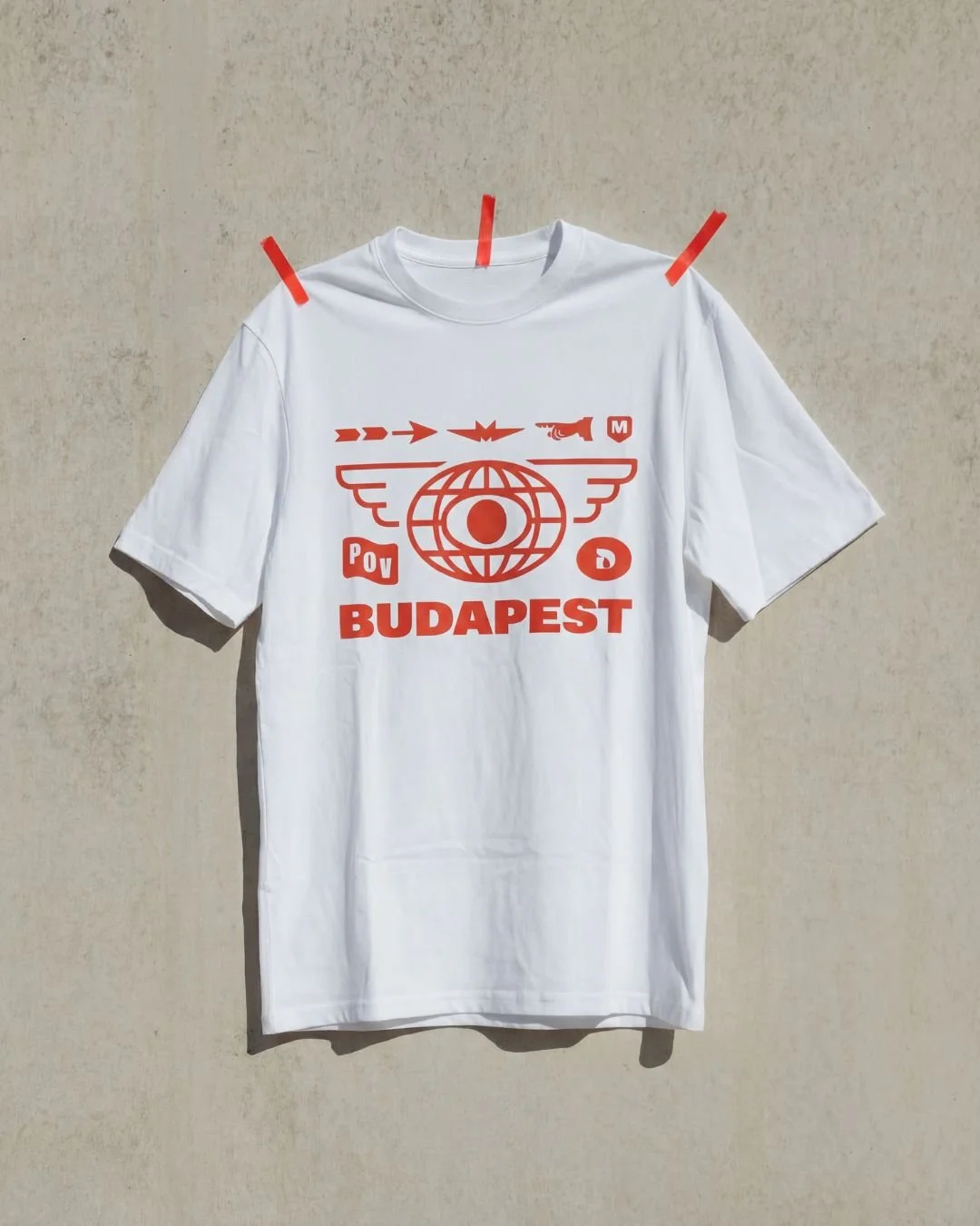White T-shirt with red graphic design featuring a globe with wings, the word 'BUDAPEST', and various symbols and text.
