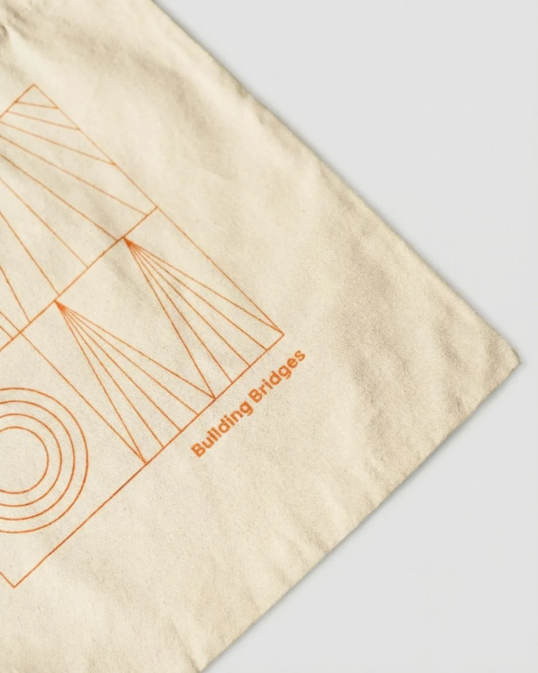 A close-up view of a beige fabric with an orange line drawing of building bridges and the text 'Building Bridges' printed on it.