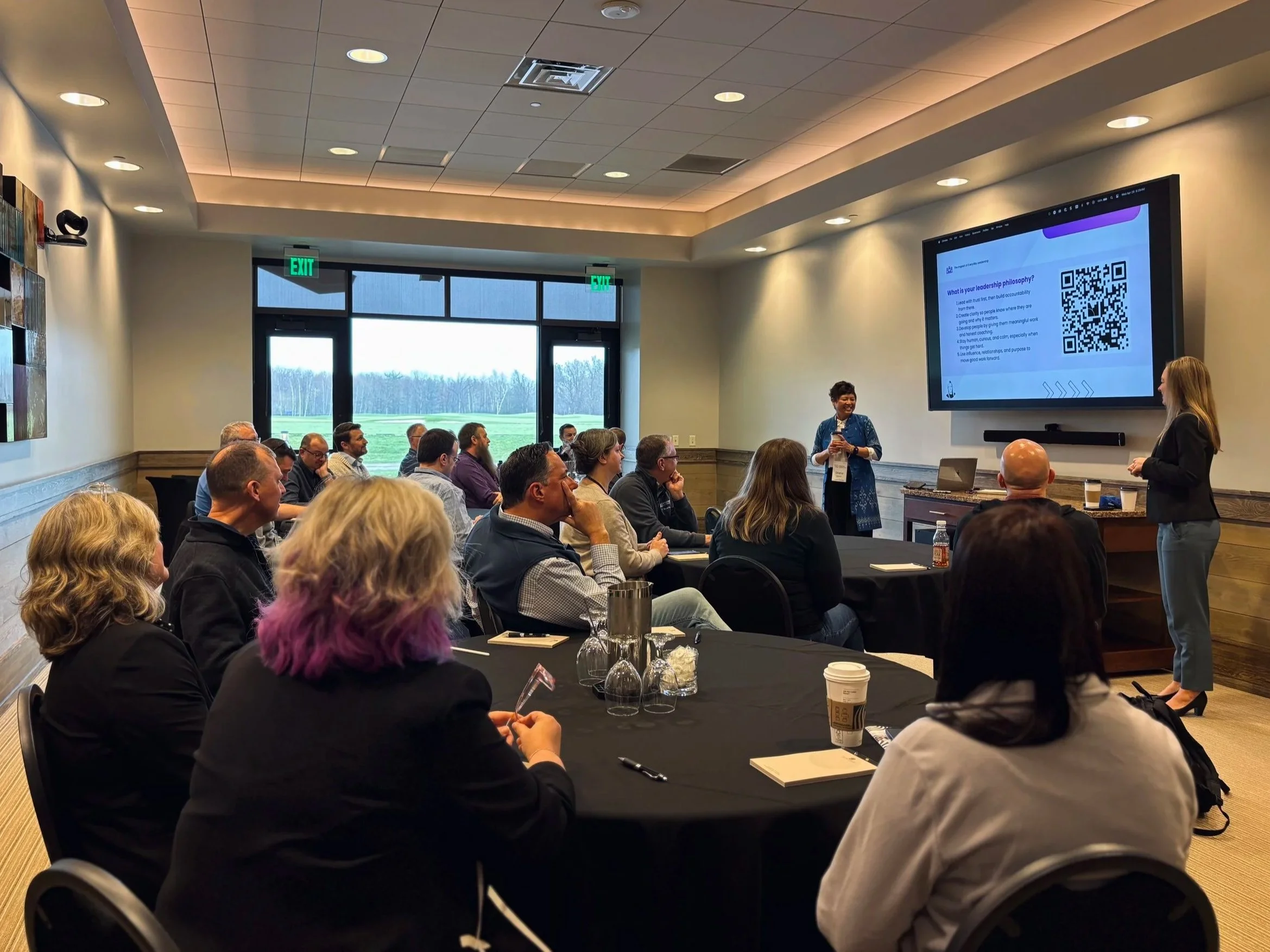 Two women lead a session in a conference room filled with attendees looking at their presentation