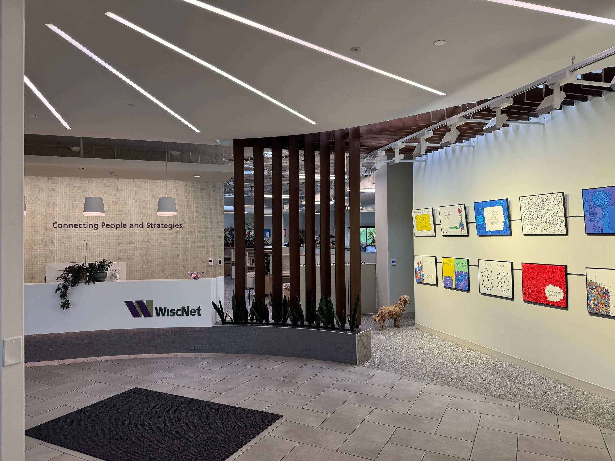 The front entrance of an office with colorful pictures on the wall and wording on the other wall that says "Connecting People and Strategies"