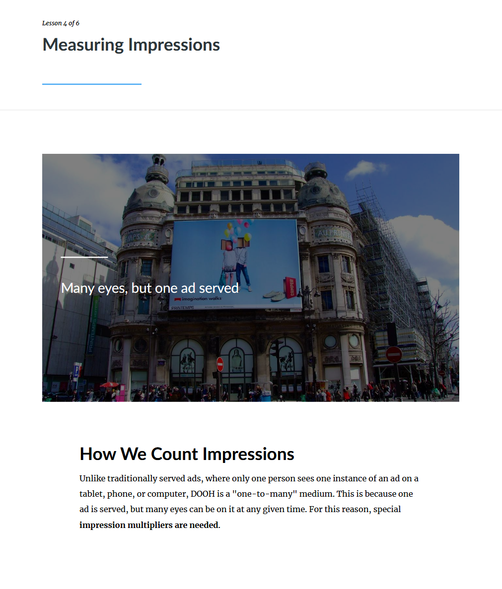 A city scene with a large building featuring a prominent billboard displaying two people holding balloons, under a partly cloudy sky. There are people walking on the street in front of the building.