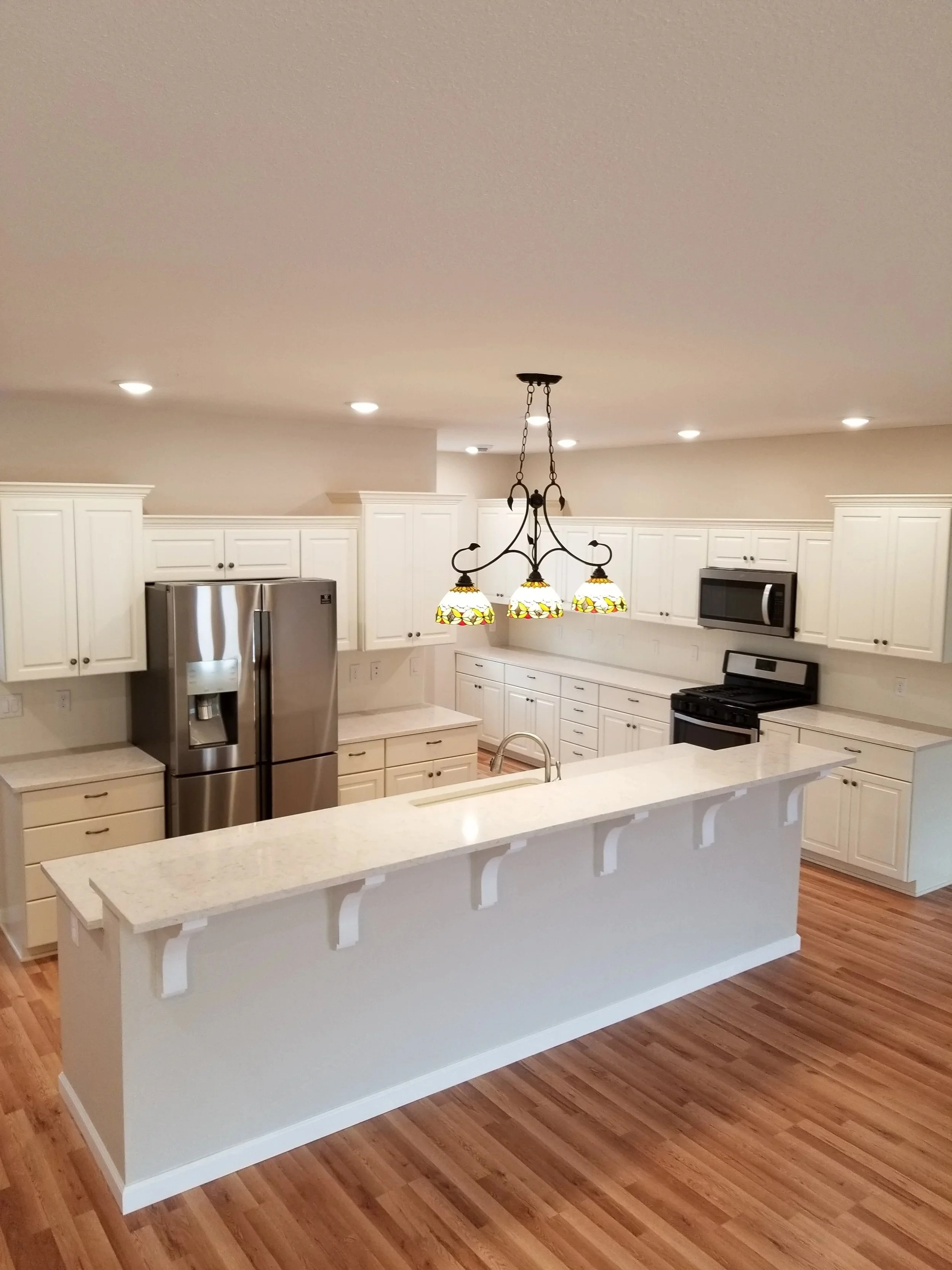 A spacious kitchen with white cabinets. Hardwood floors complete the room.