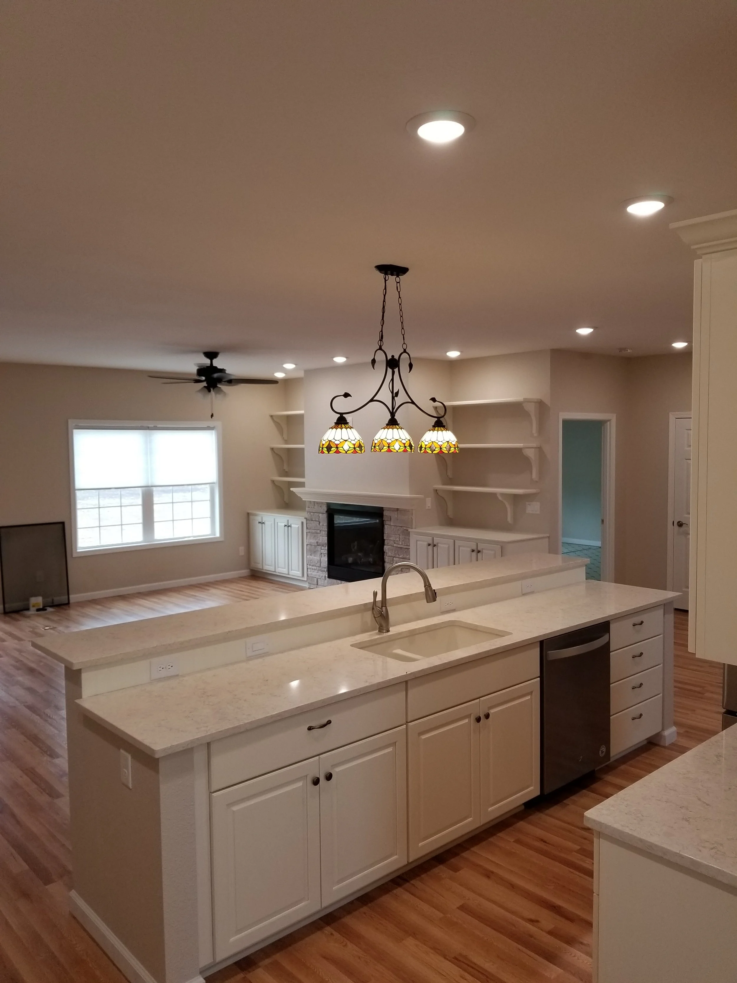 Open-concept living space with kitchen island, a fireplace with built-in shelves