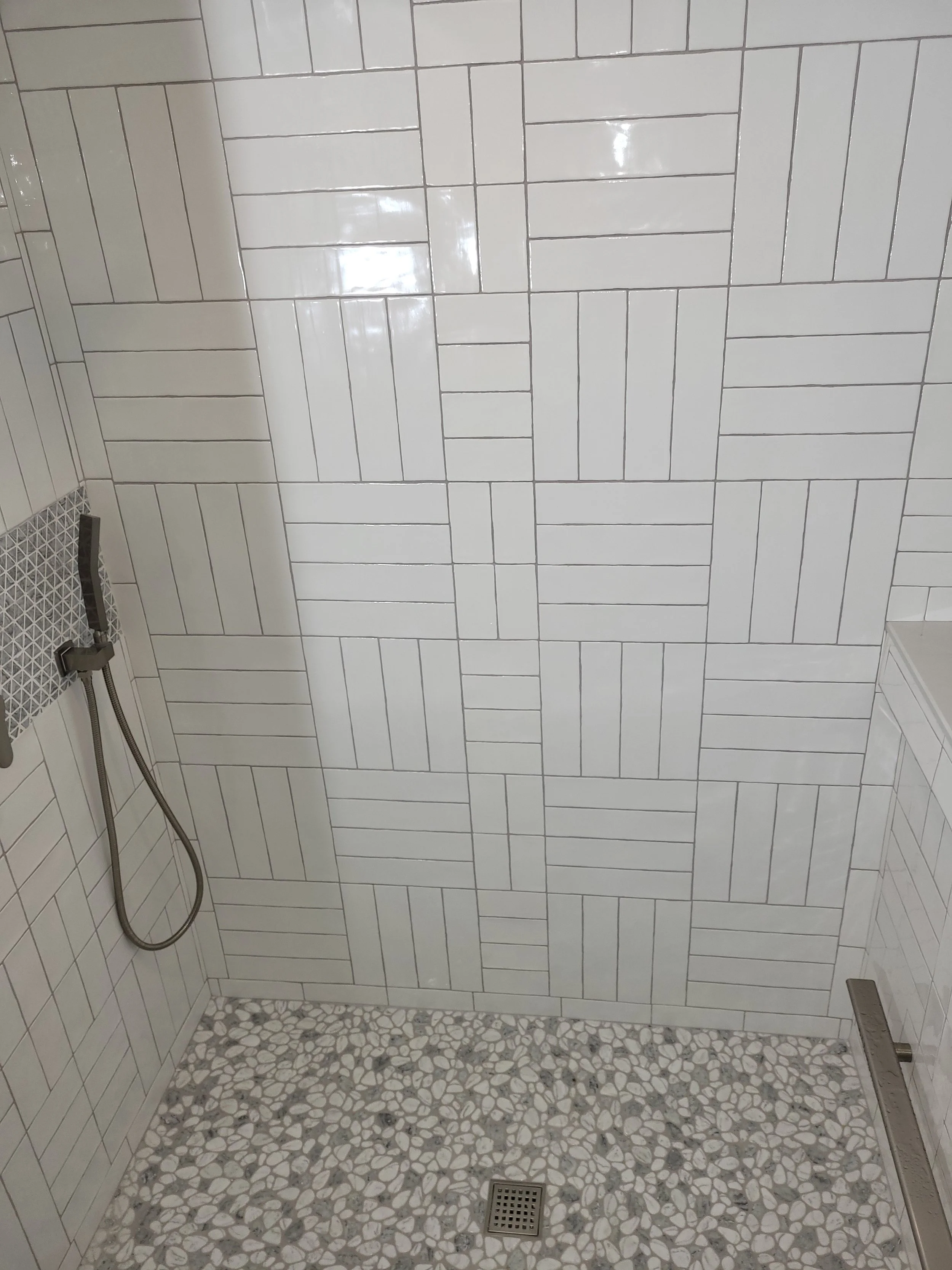 A tiled shower with custom pattern, foot rest and waterproof epoxy grout