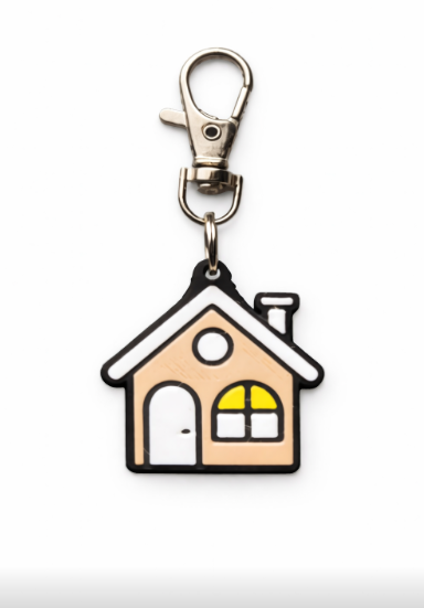 A house-shaped keychain with a silver clasp, featuring a cartoon house with a door, a round window, and a yellow and white arched window.