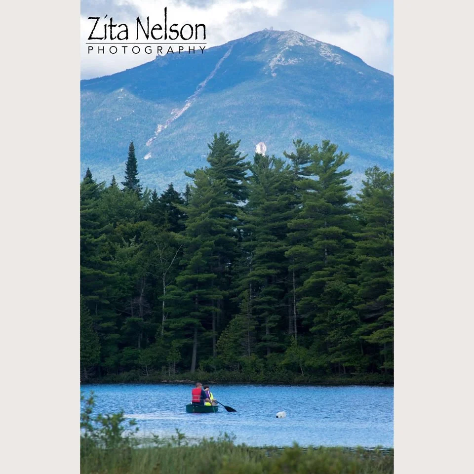 Photograph of Mountain side with kayakers in Lake Placid