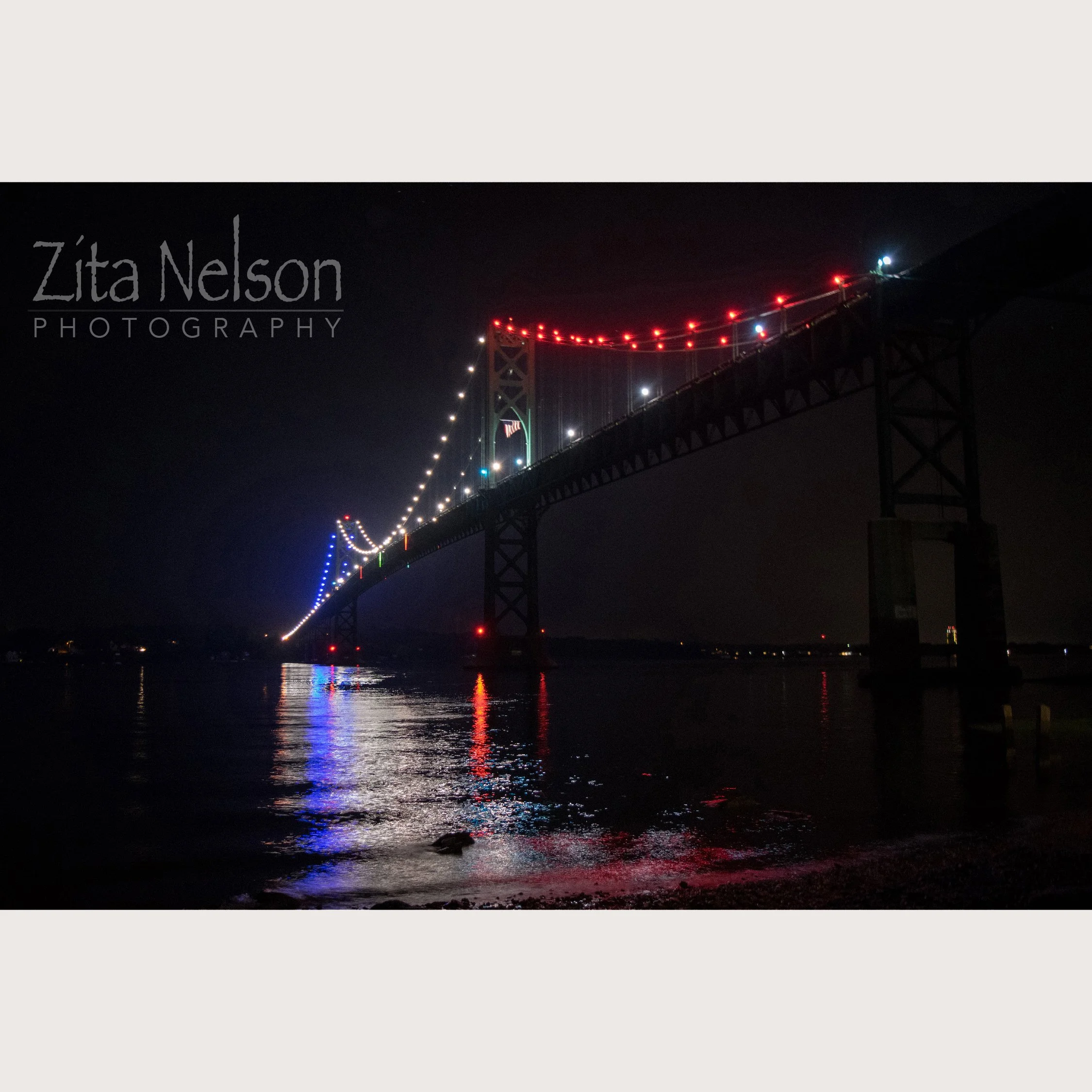 Photograph of Mount Hope Bridge at night from Bristol RI side with Red White and Blue Lights 