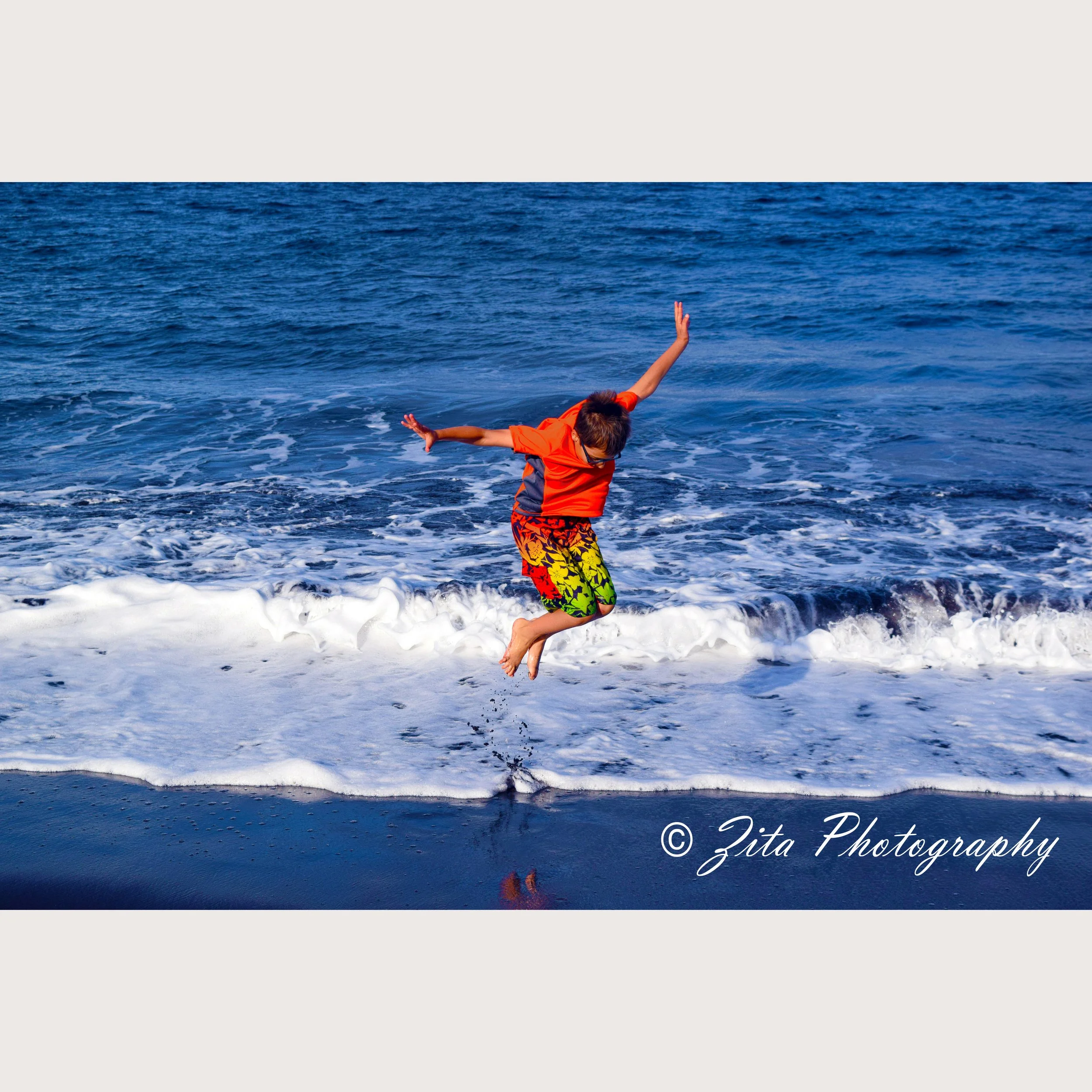 Child jumping in the air by the shoreline
