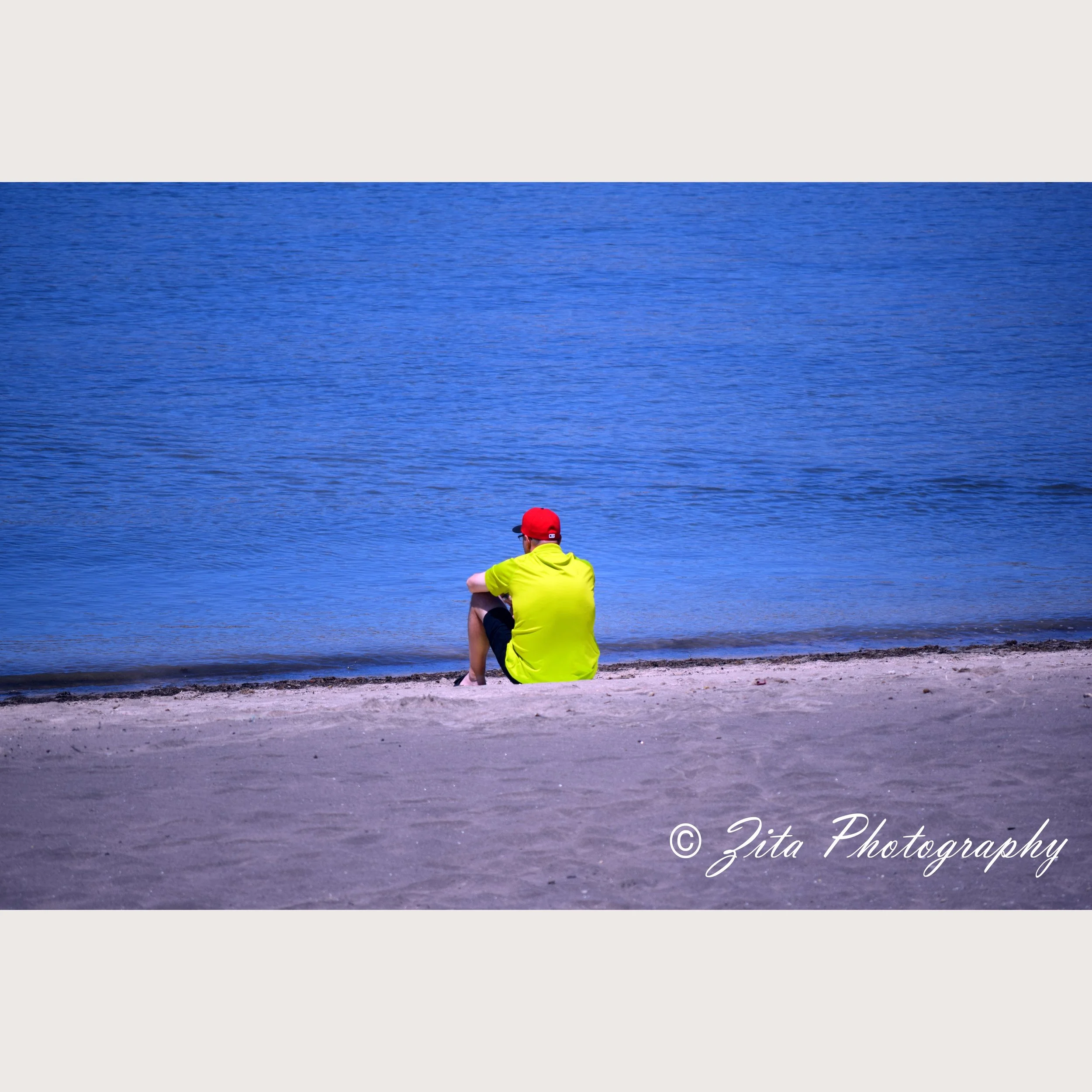 Photograph of man sitting at waters edge