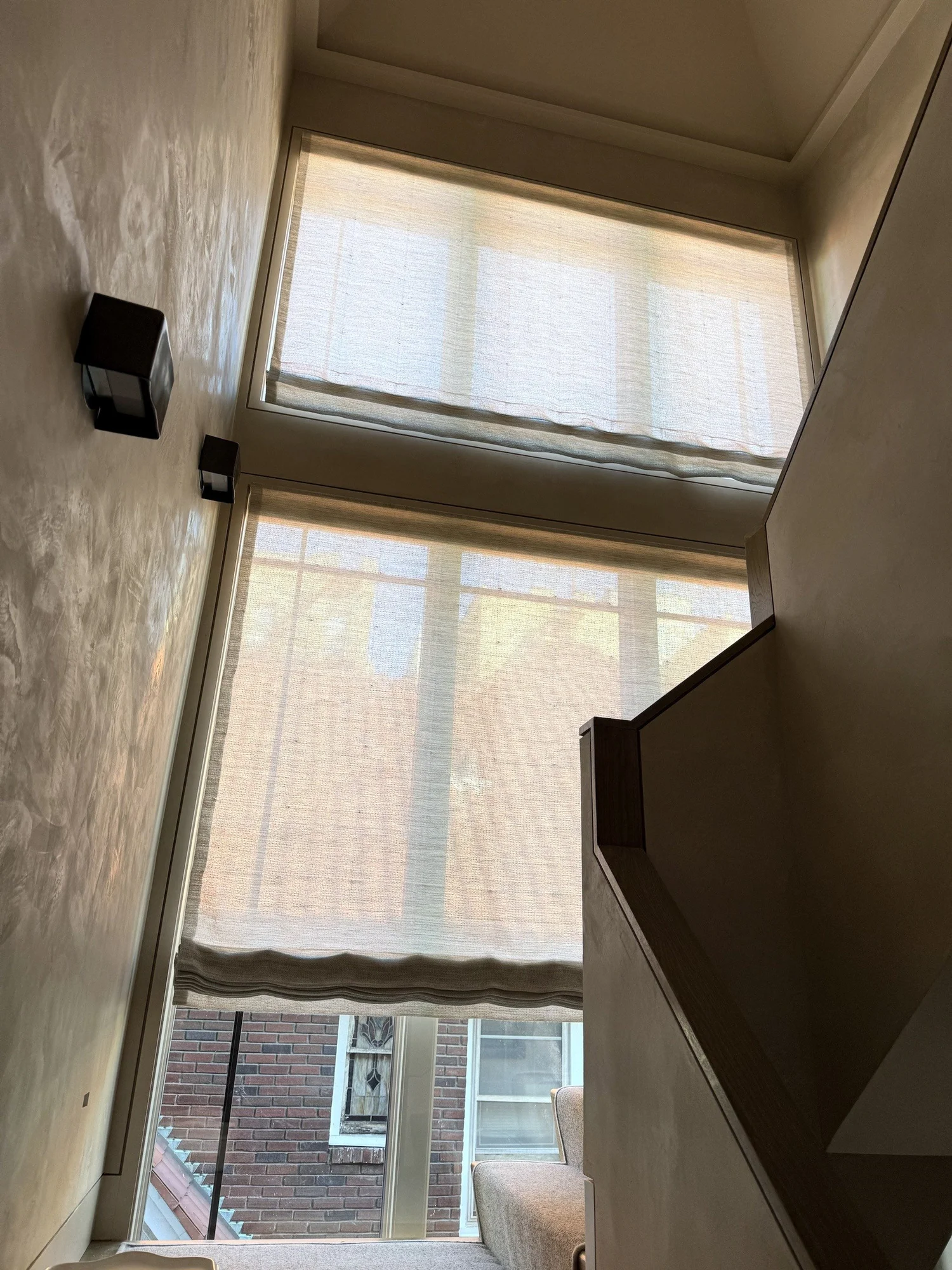 Stacked linen Roman shades on a double-height stair hall window in New York