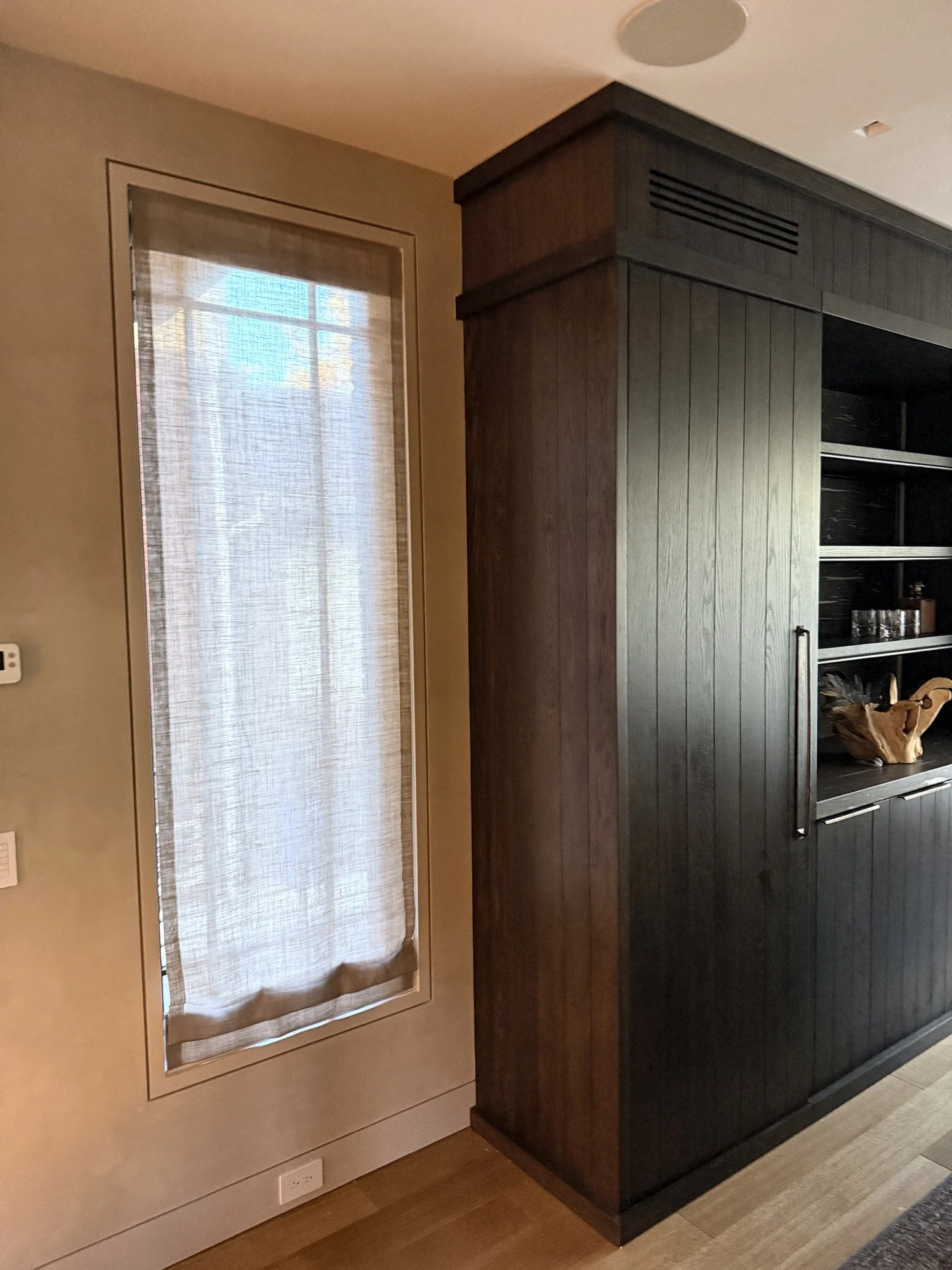 Linen Roman shade on a tall recessed window beside custom millwork in New York