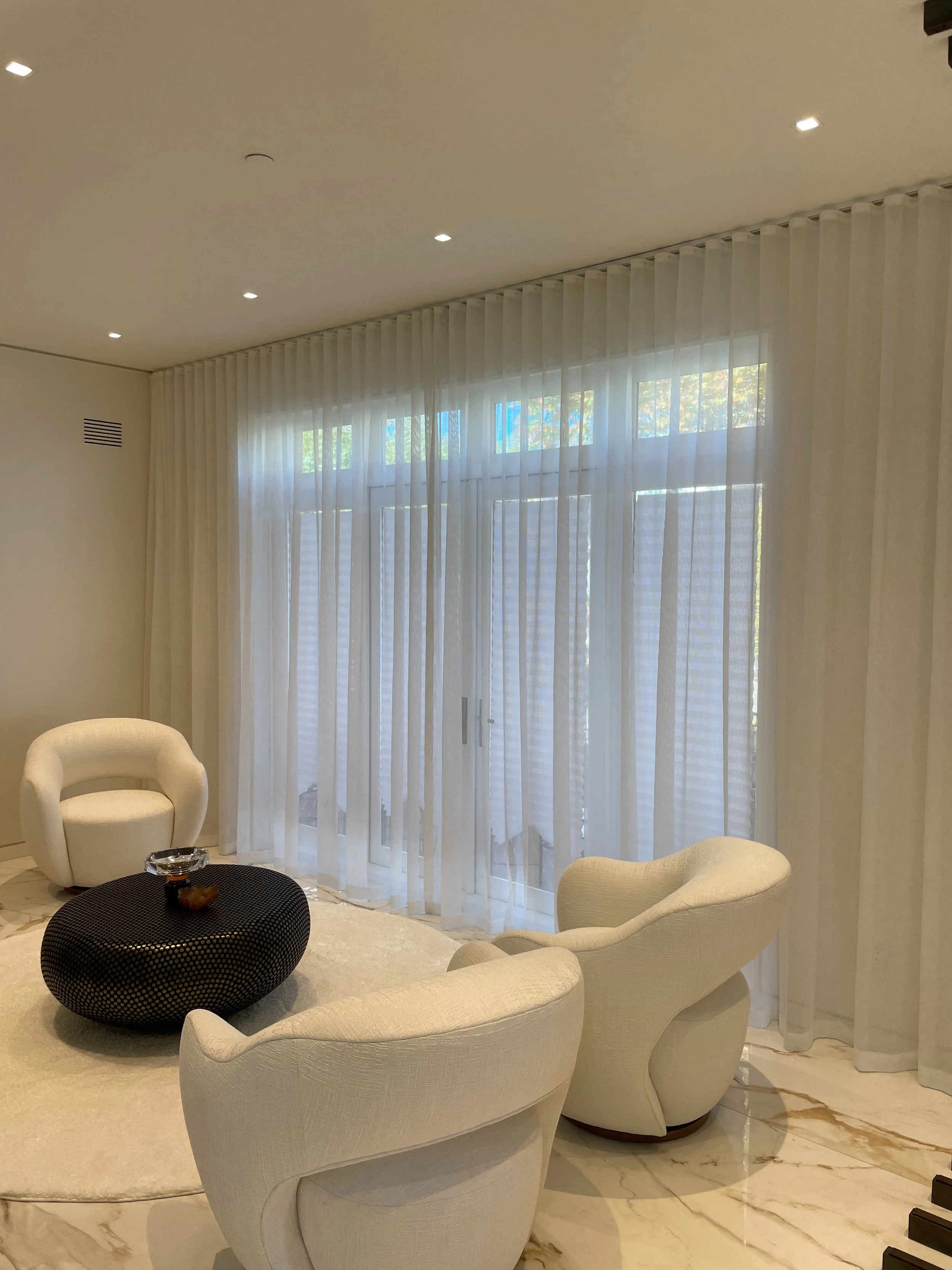 Minimalist luxury living room with floor-to-ceiling sheer white ripple-fold drapery on ceiling track, marble floors, NYC