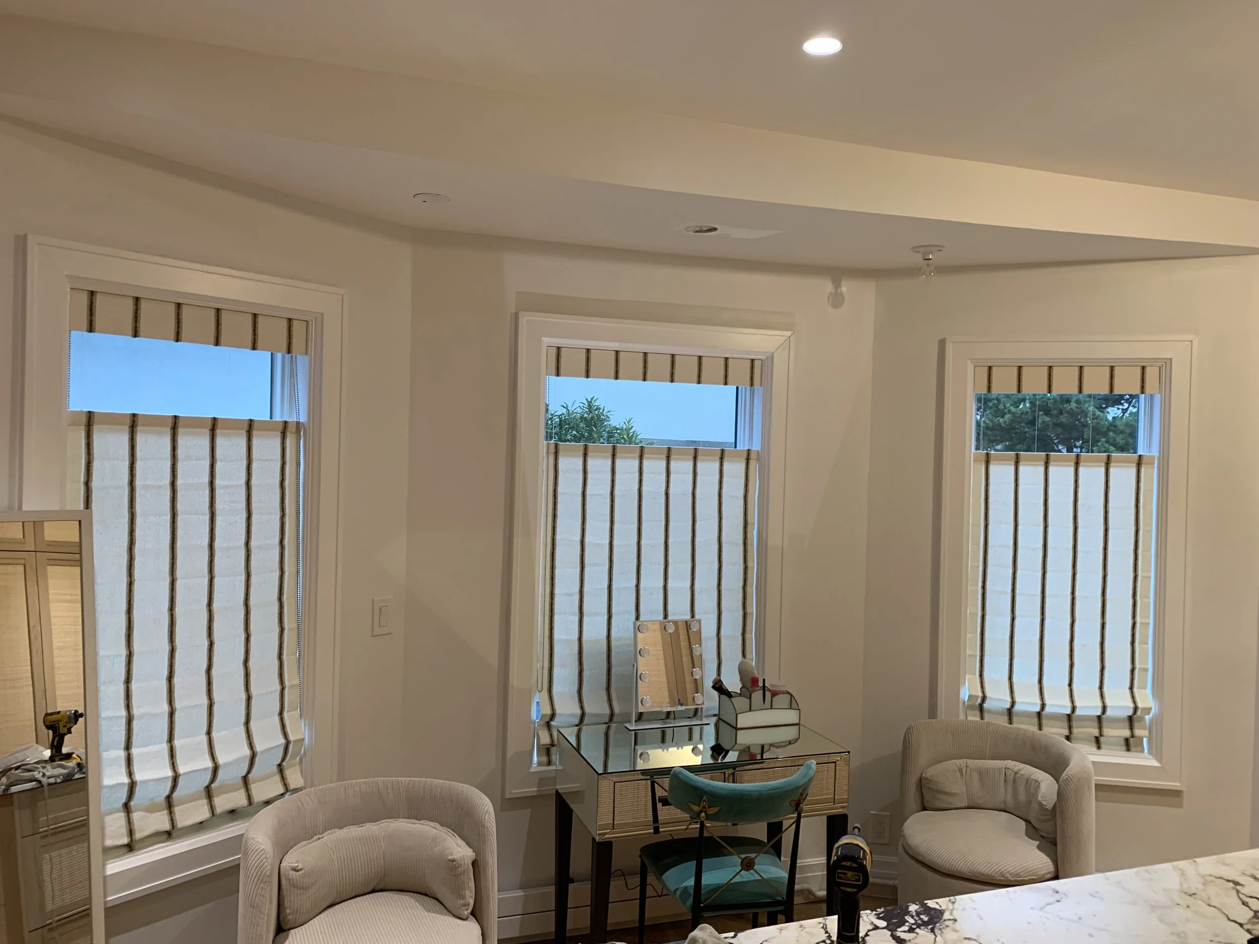 Triple bay window with custom woven bamboo roman shades in dressing room with vanity and boudoir chairs, NYC