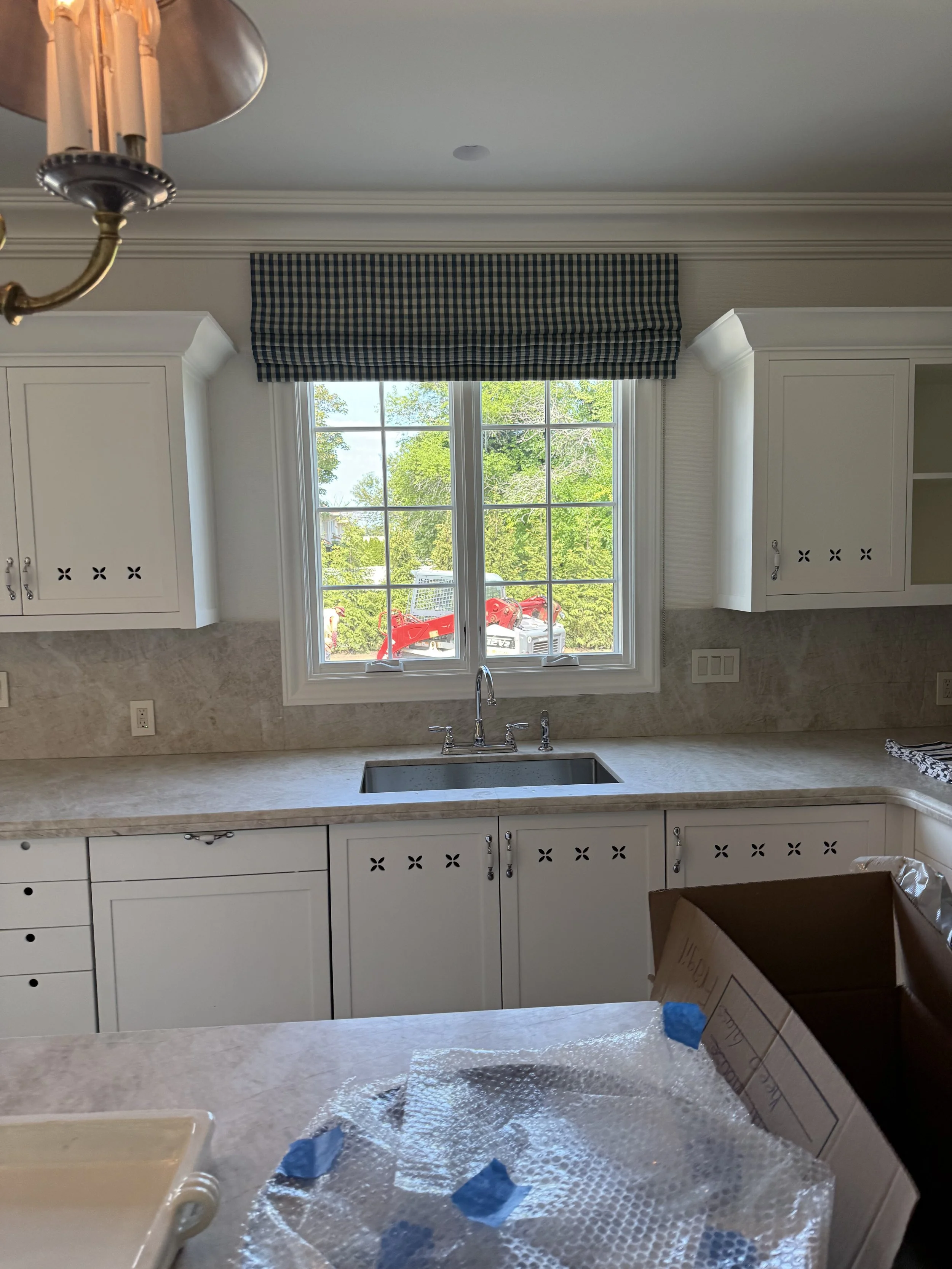 Custom plaid roman shade installed over kitchen window with marble countertop, NYC Rafael Interiors
