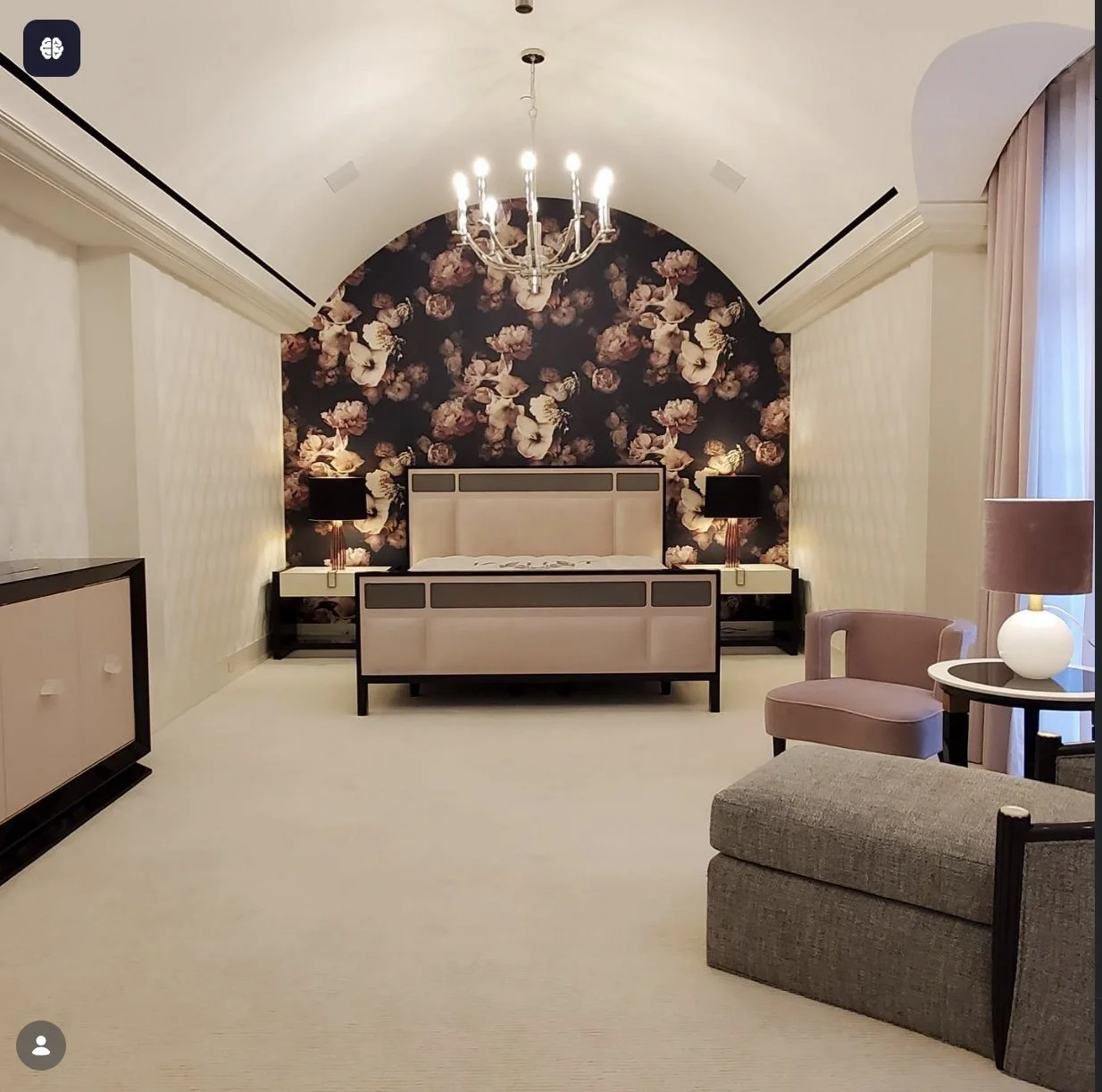 Dramatic master bedroom with arched floral wallpaper accent wall, barrel vault ceiling and chandelier