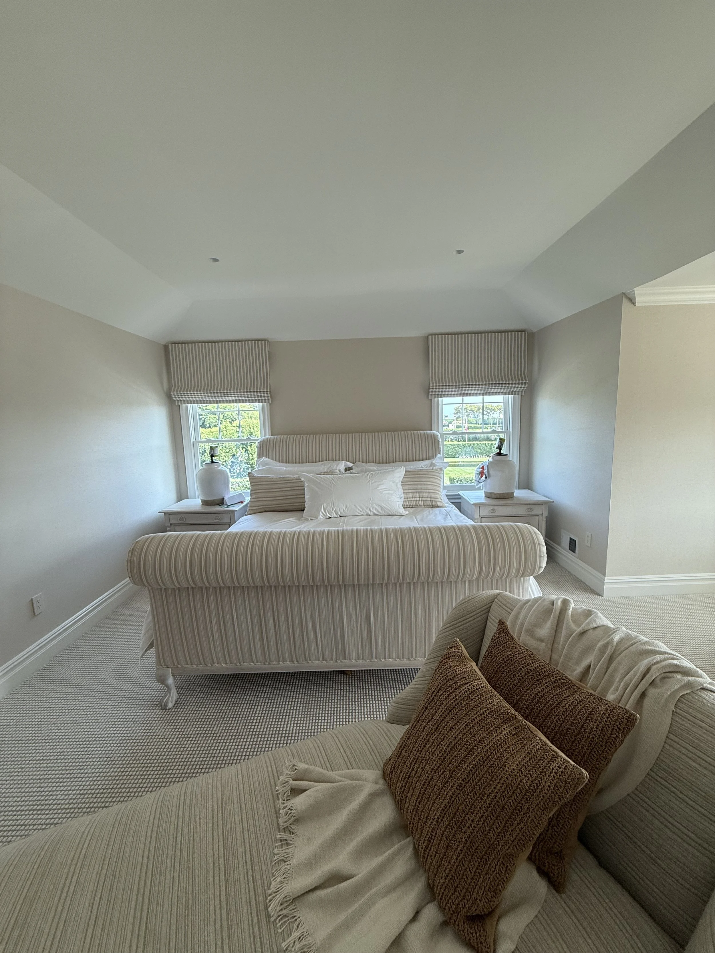 Neutral roman shade in master bedroom with upholstered bed and coordinating accent pillows, NYC
