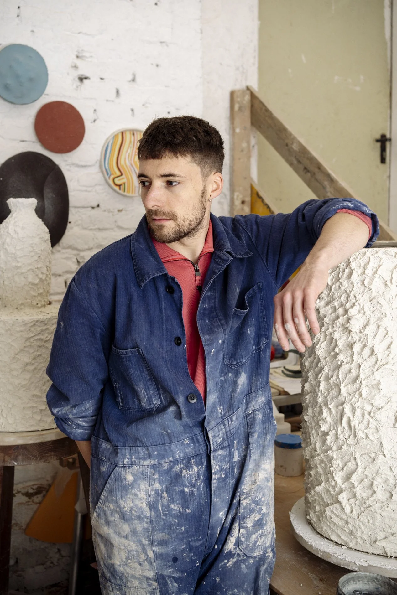 Junge Keramikkünstler in Werkstatt mit Ton und Skulpturen