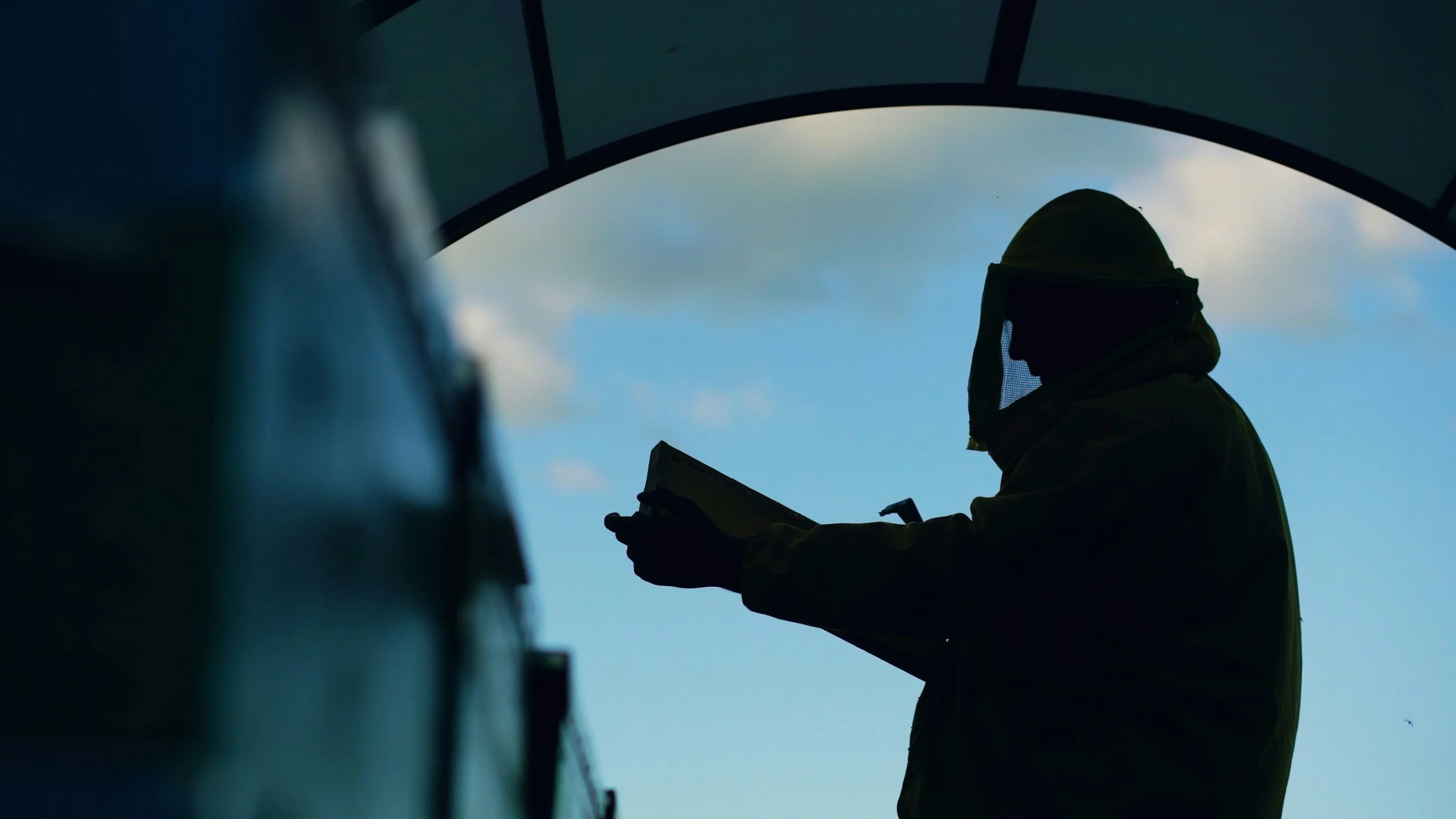 Persona con equipo de protección inspeccionando o revisando documentos en un espacio cerrado con cielo visible en el fondo.