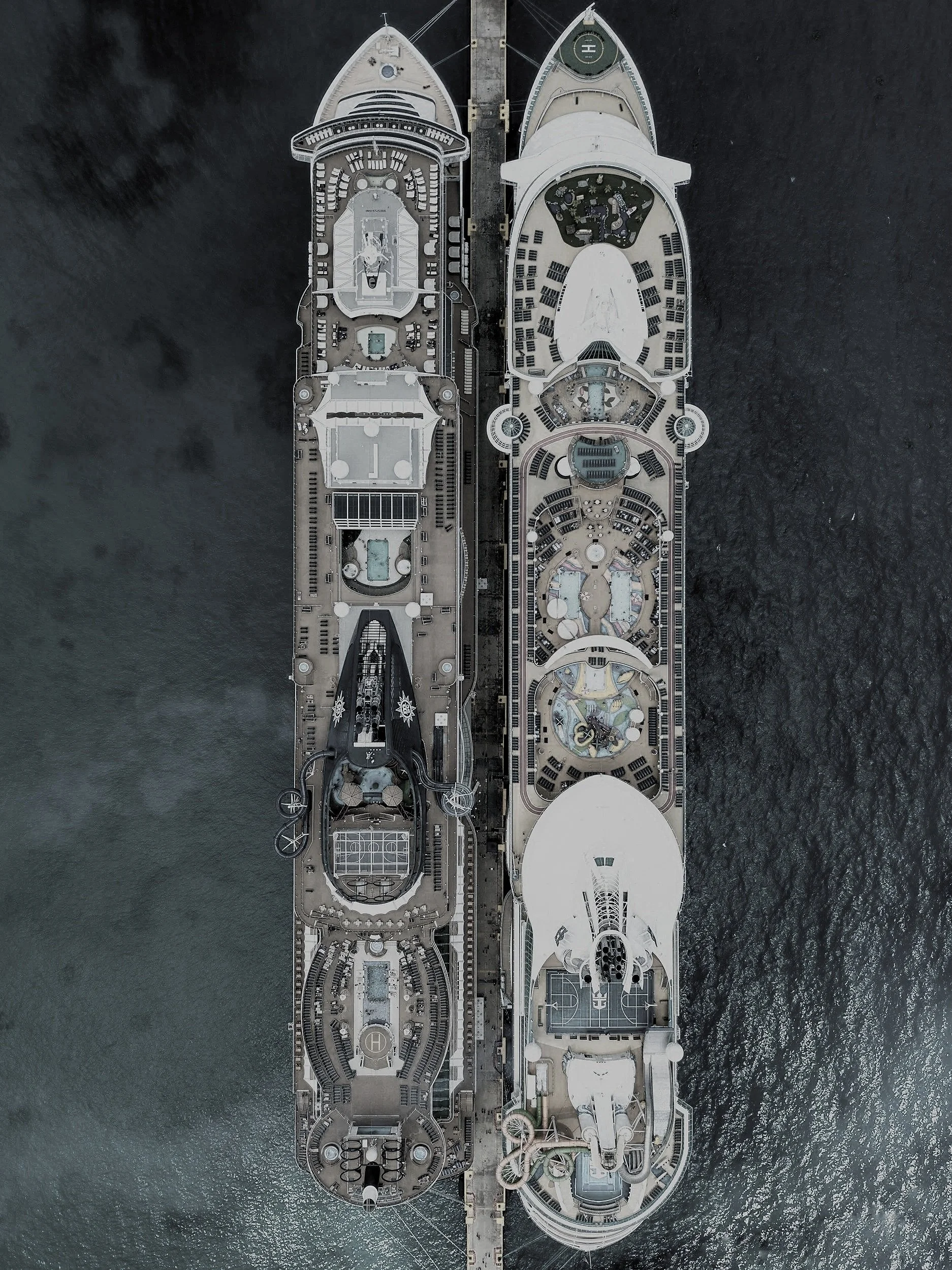 Vista aérea de dos cruceros atracados en un muelle, rodeados por agua y con áreas recreativas visibles en las cubiertas