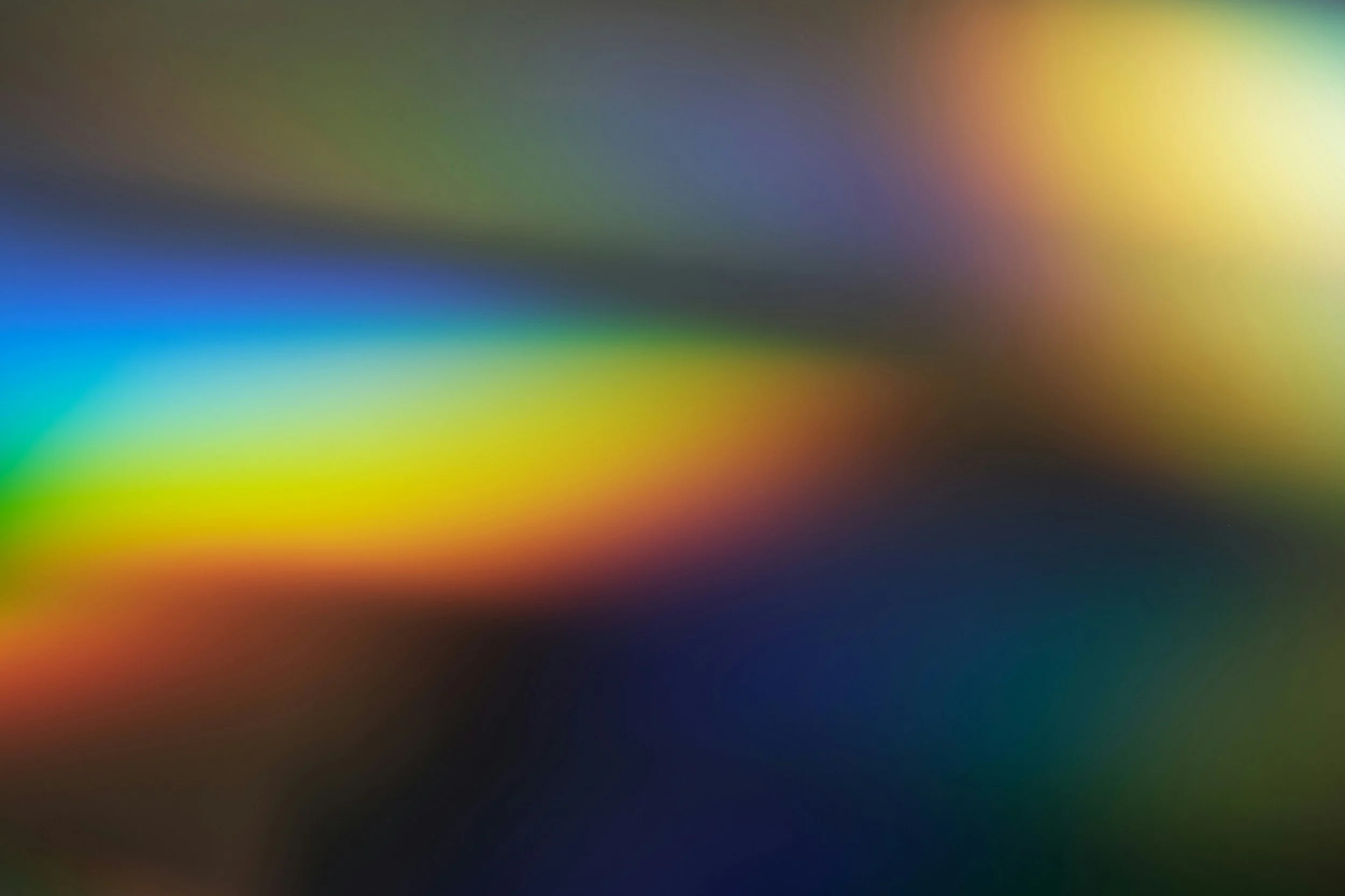 Blurred abstract image with vibrant streaks of color including blue, green, yellow, red, and purple.
