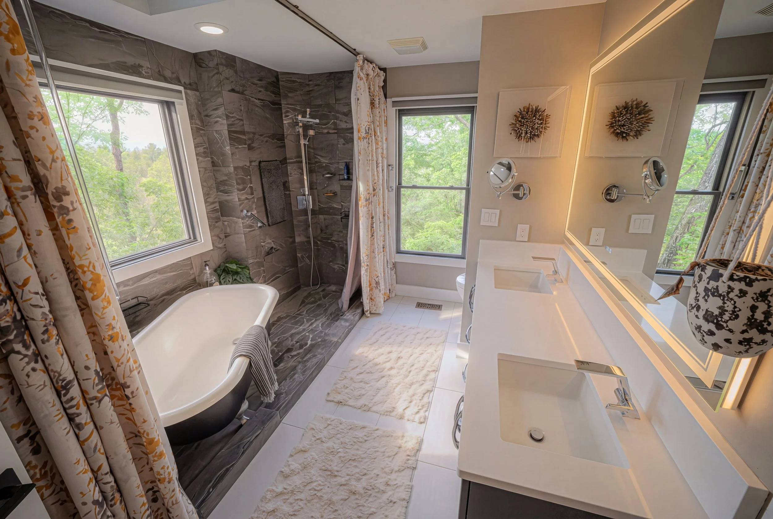 Front view of a blue house with wooden shutters, a small porch with stone steps, potted plants, and a garden bed with plants.