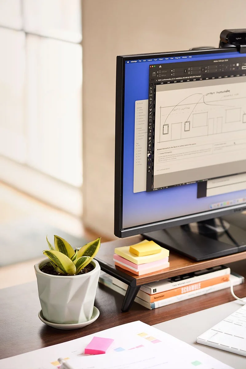A clean office desk featuring a computer monitor displaying a digital architectural sketch.